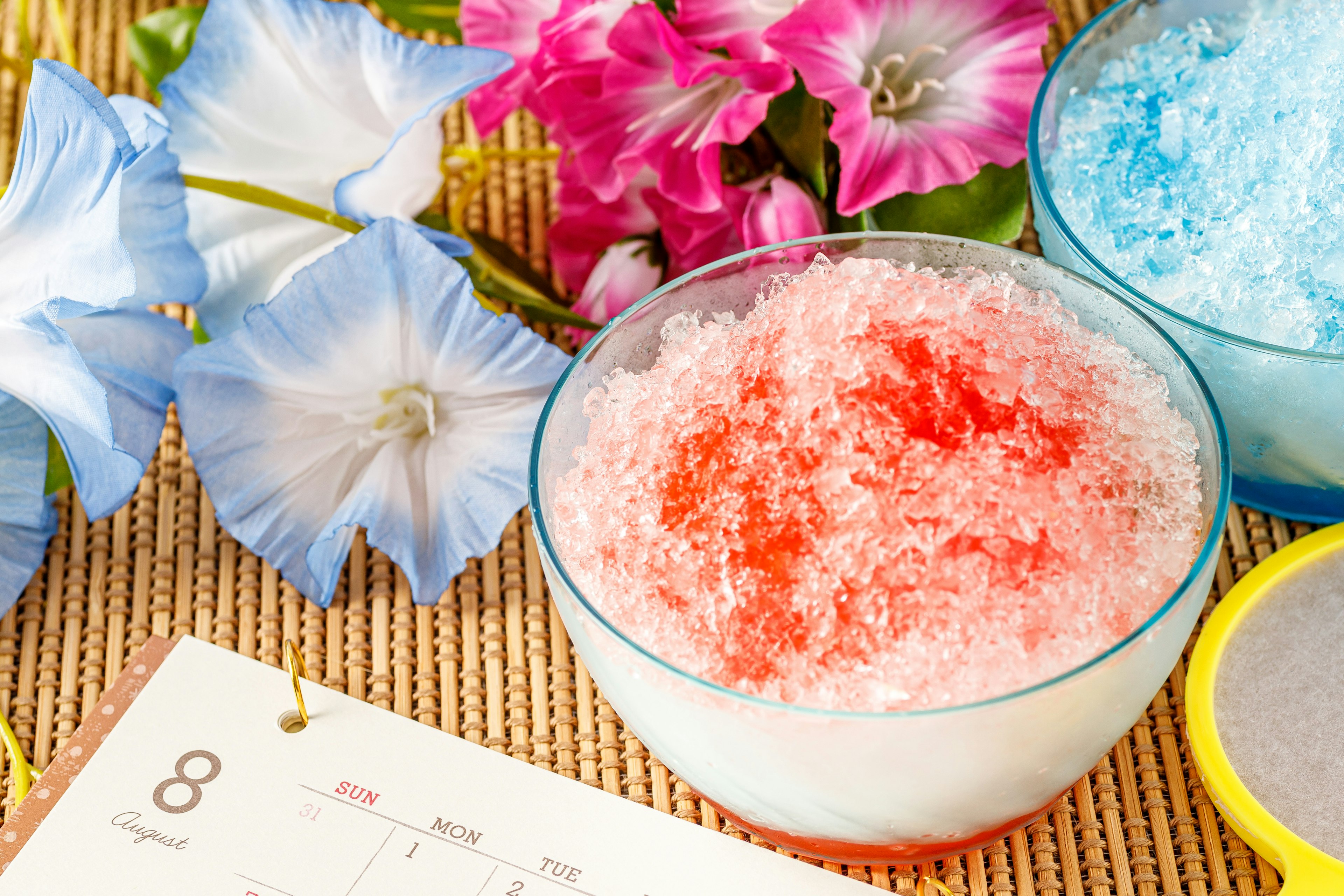 Colorful bowls of shaved ice and flowers creating a summer dessert scene