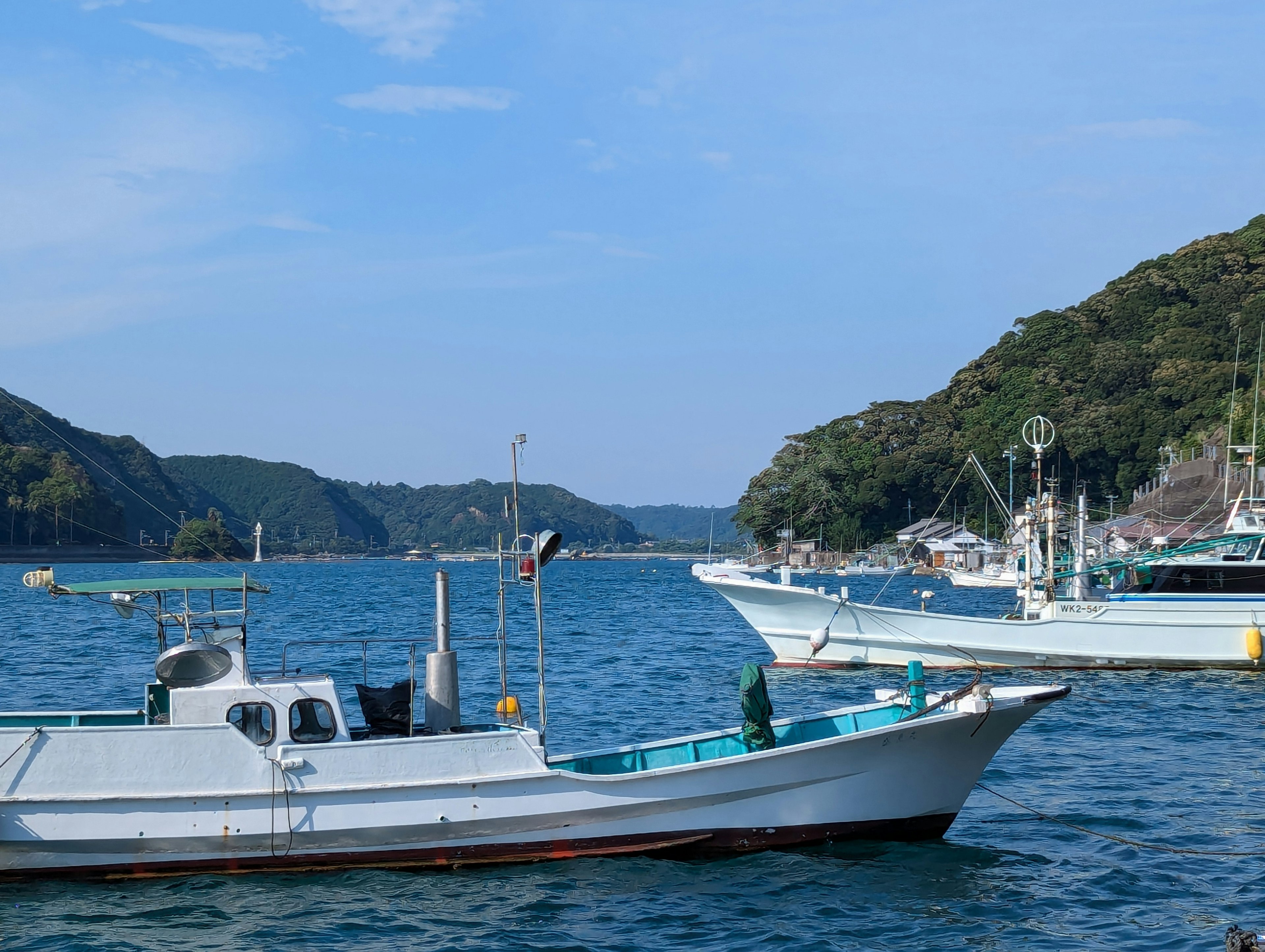 Fishing boats on a calm sea with scenic hills in the background