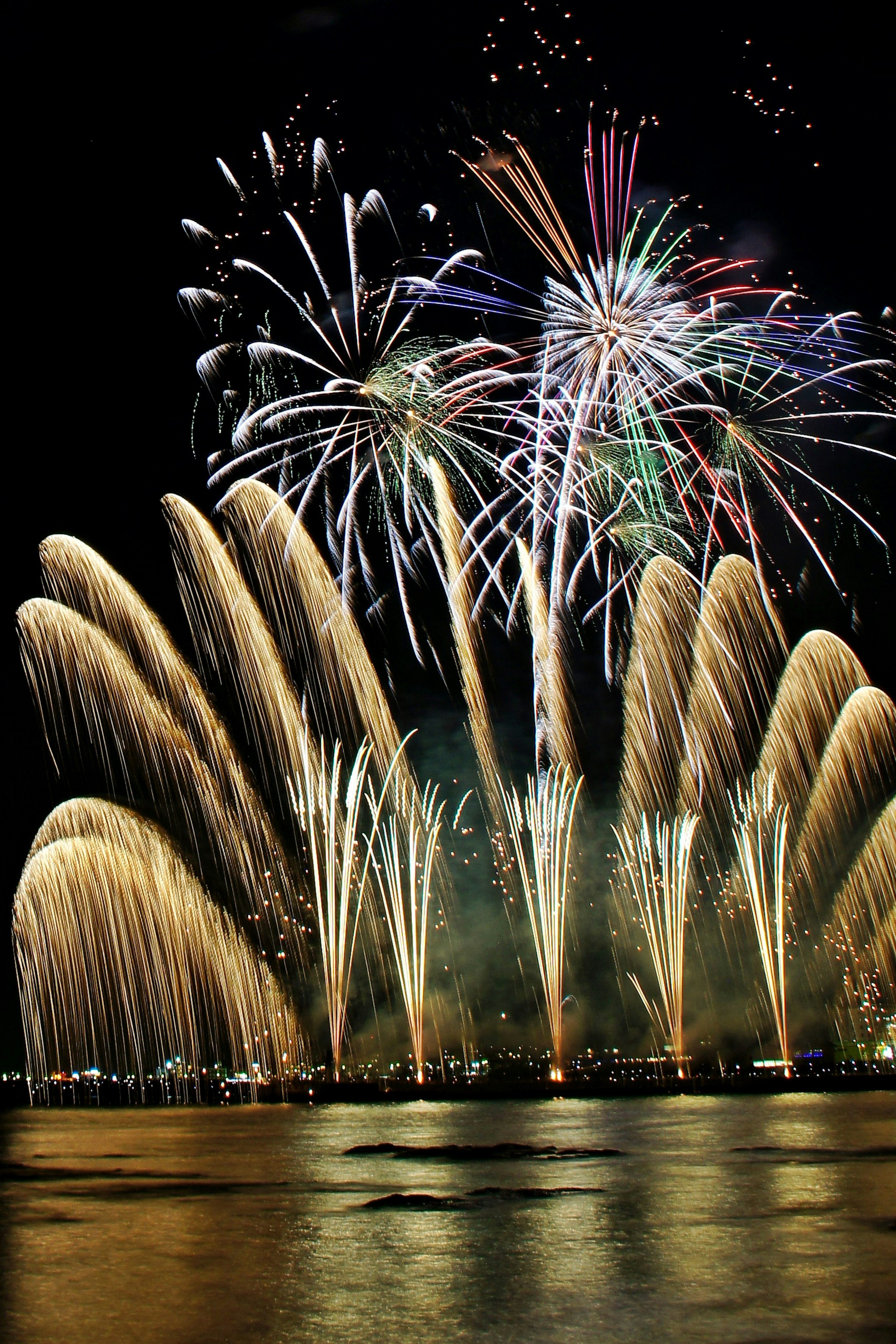 Colorful fireworks lighting up the night sky reflecting on the water