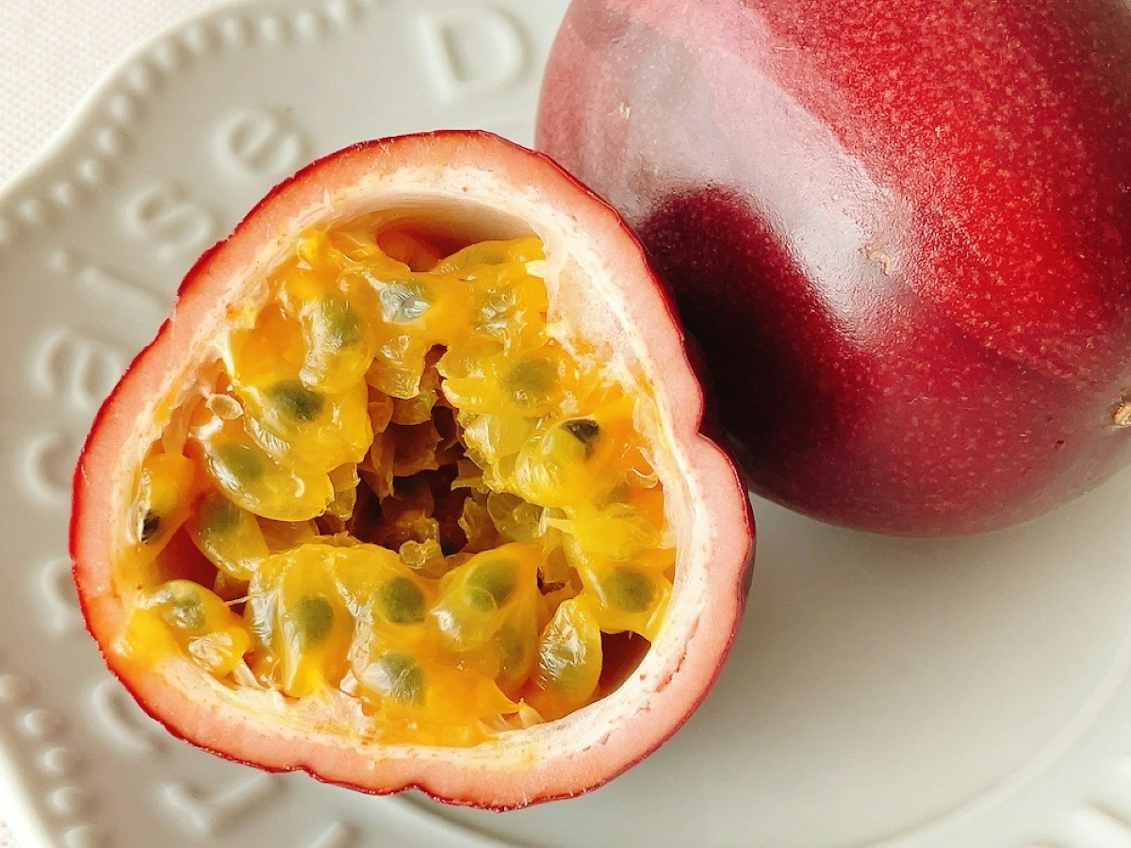 A halved red passion fruit revealing vibrant orange pulp inside