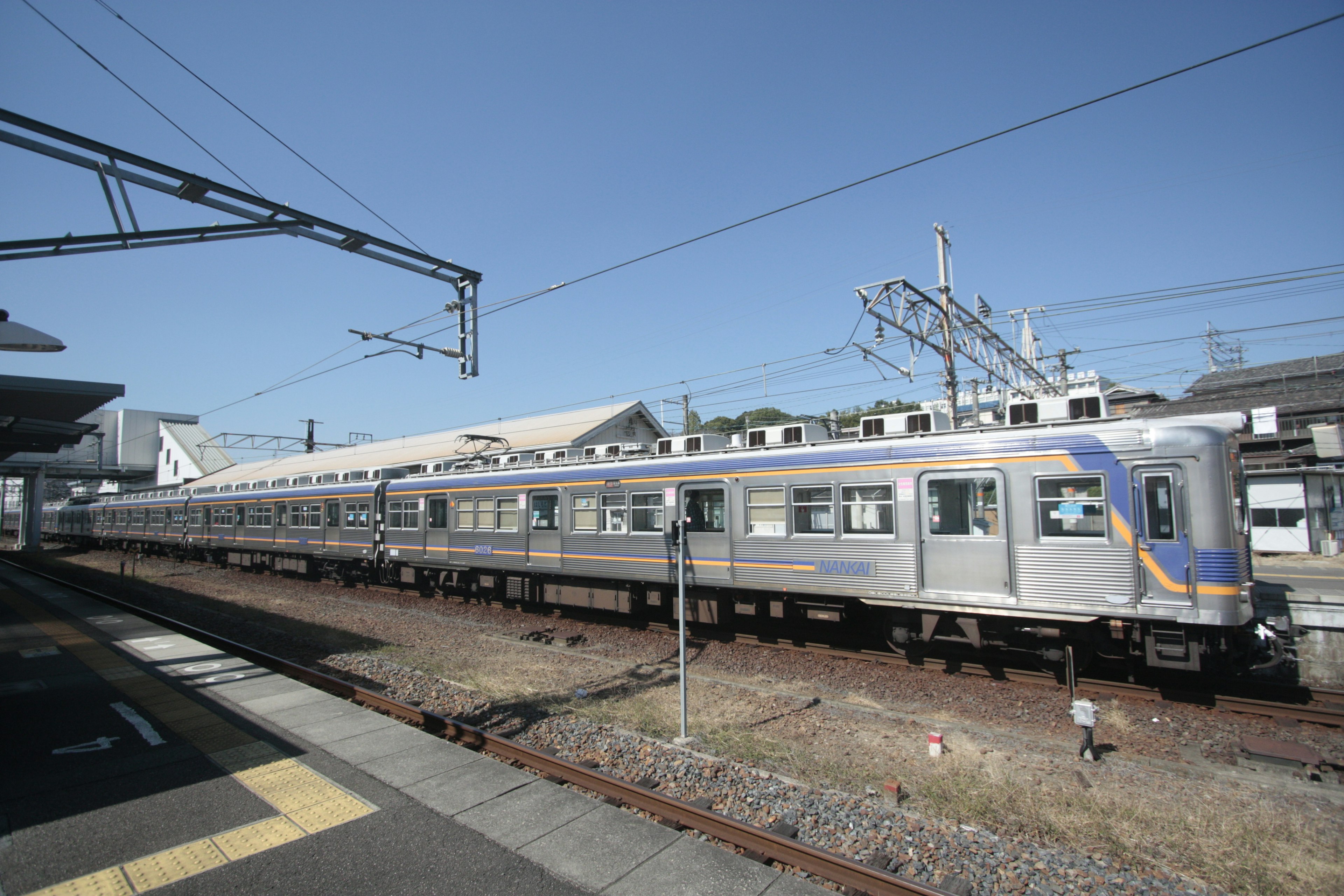 Treno argentato fermo alla stazione sotto un cielo azzurro