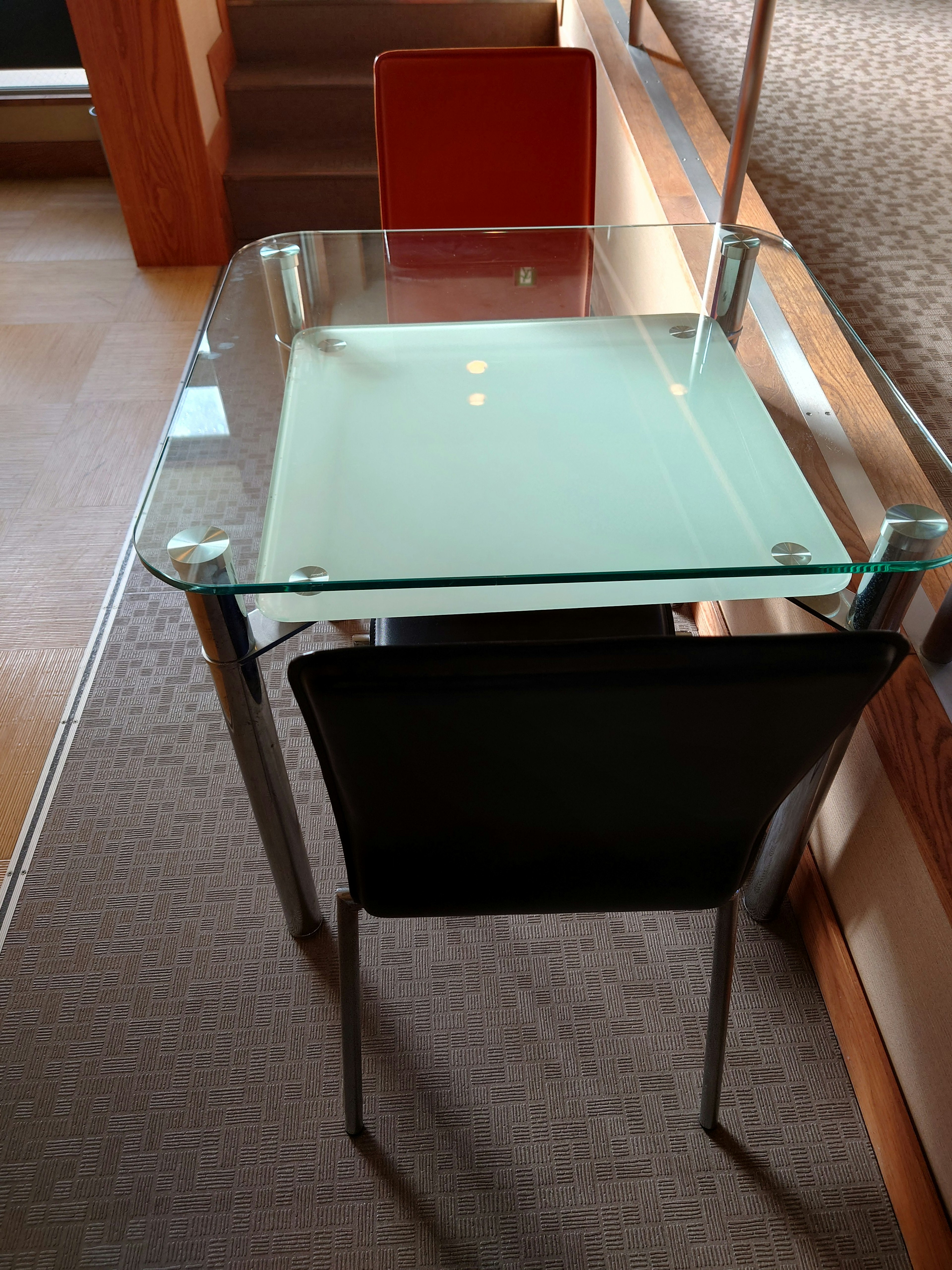 Glass table with black chair and red chair in an indoor setting