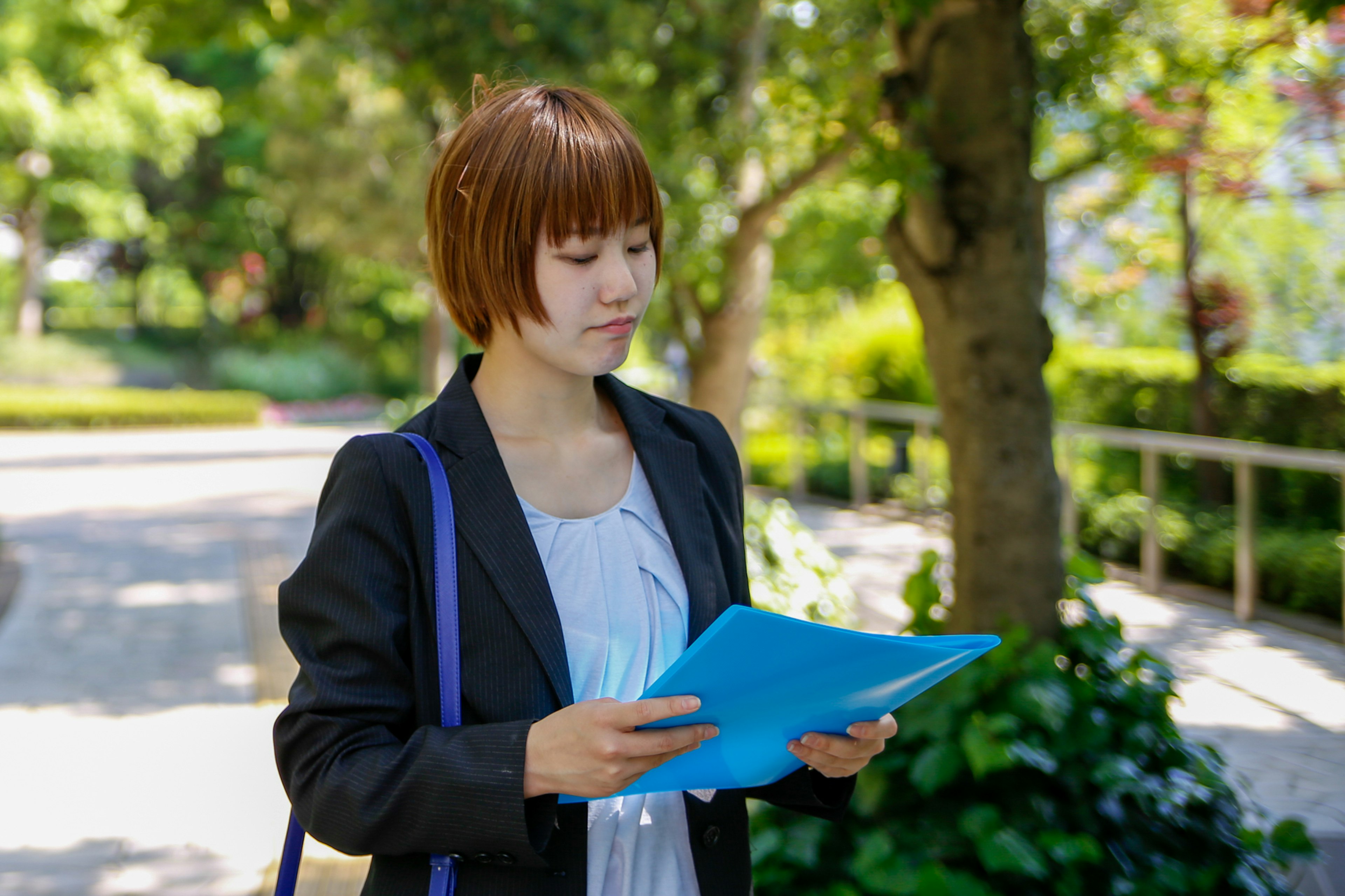 Young businesswoman holding blue documents in a park