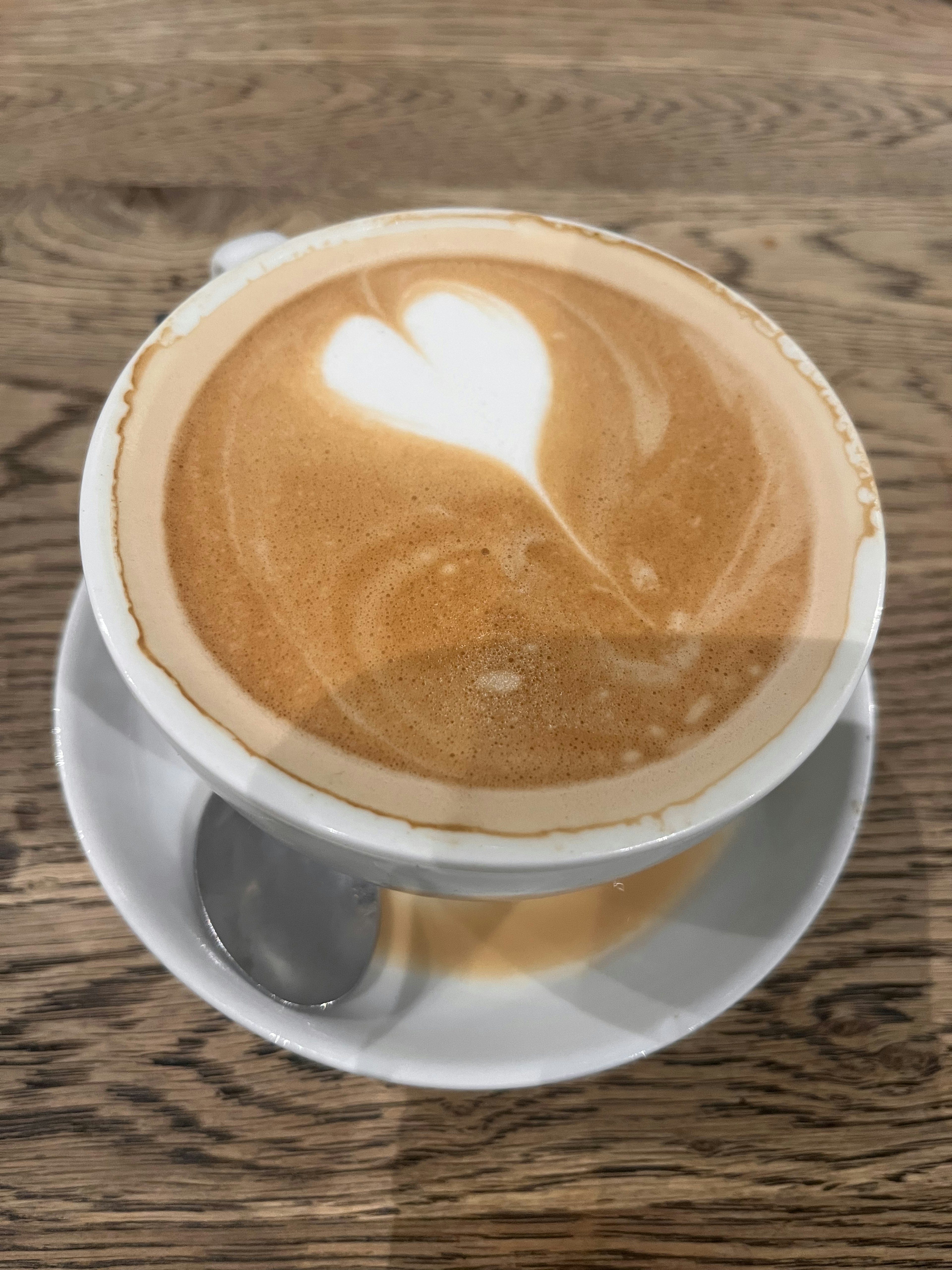 A cafe latte with heart latte art on a wooden table