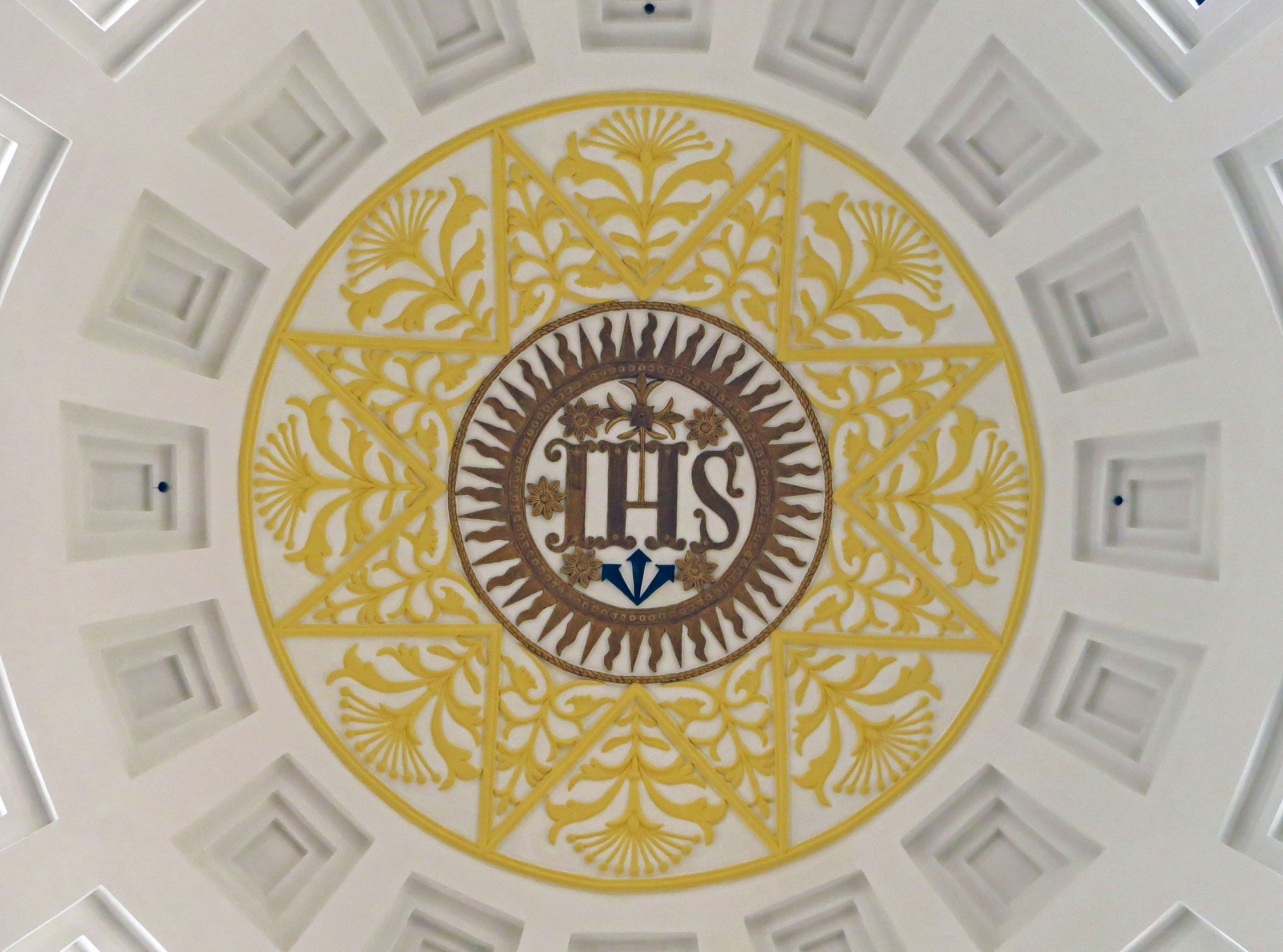 Beautiful ceiling decoration featuring golden patterns and the letters 'IHS' in the center