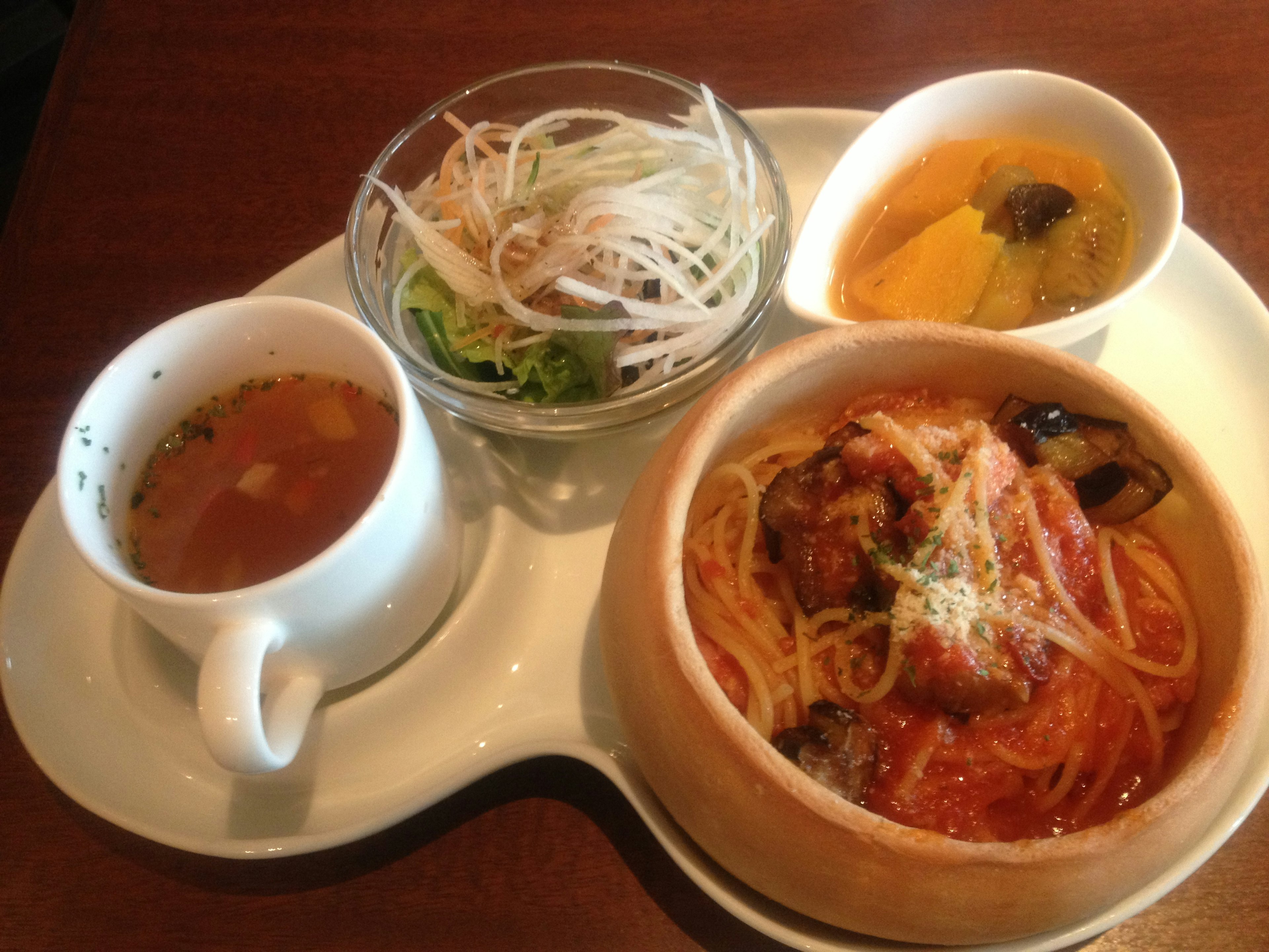 Un plato de almuerzo bellamente presentado con espaguetis, ensalada, sopa y postre