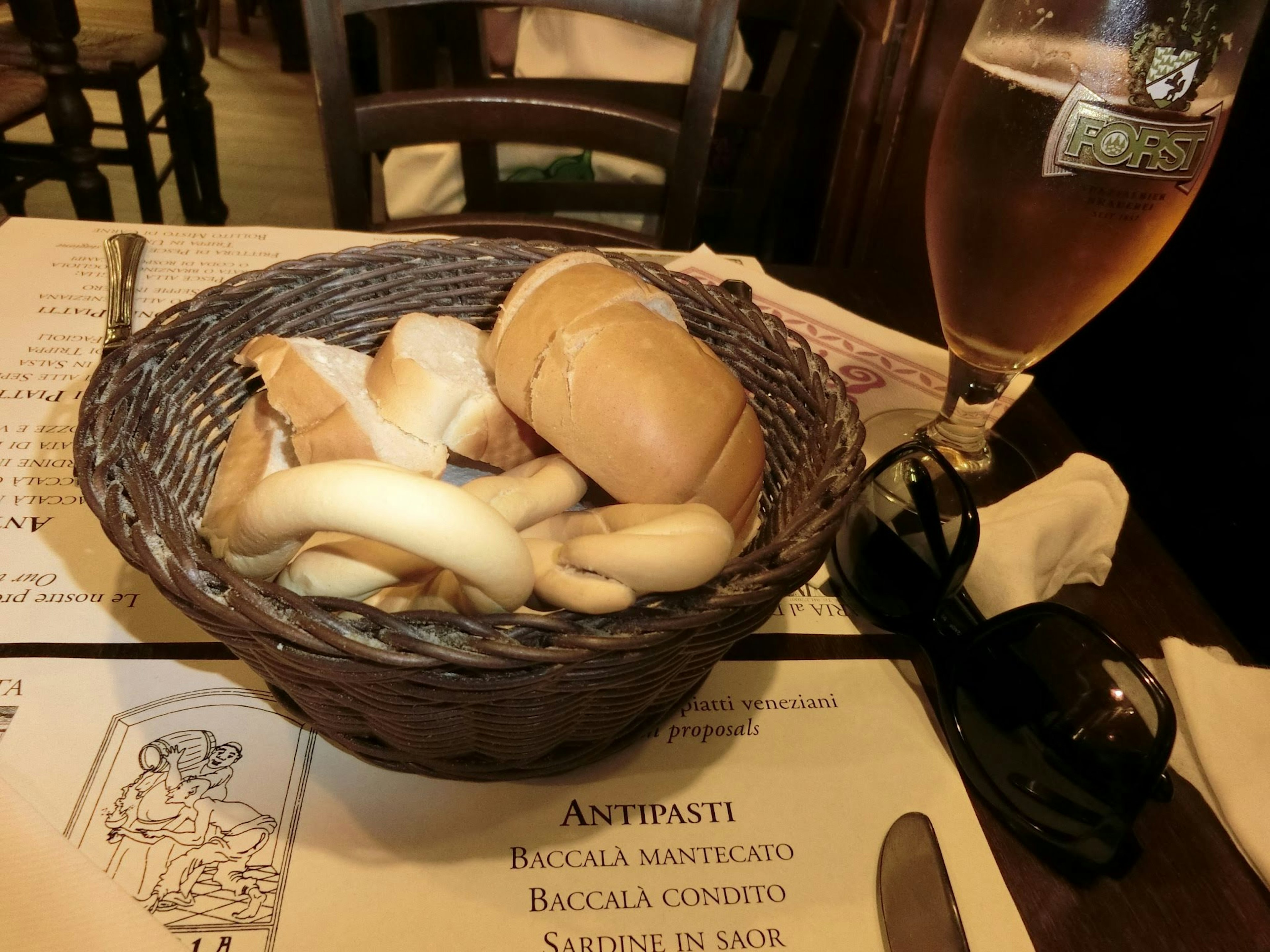 A woven basket with assorted breads and a glass of beer