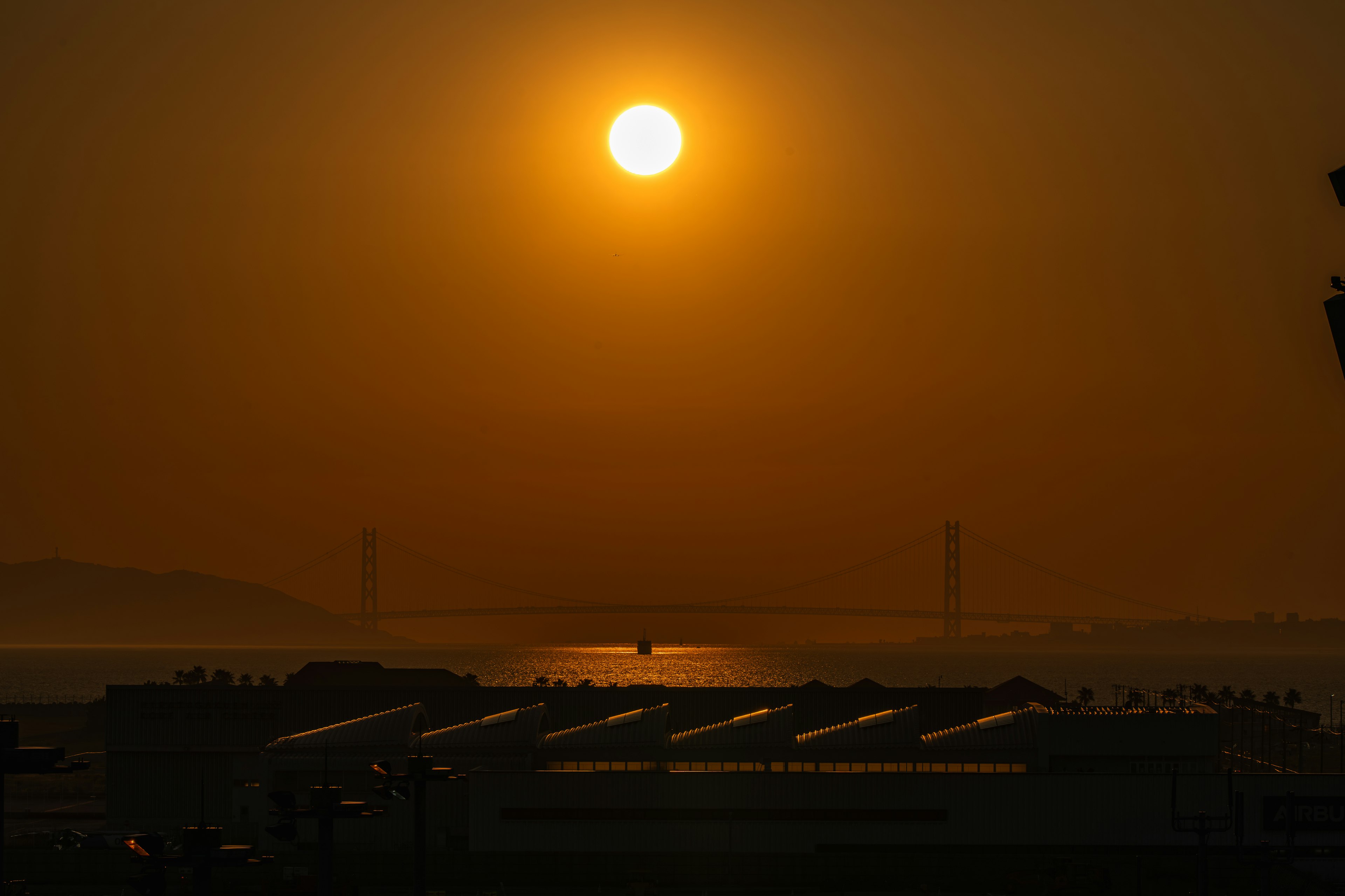 夕日が海に沈む風景とシルエットの建物が印象的な夕暮れ