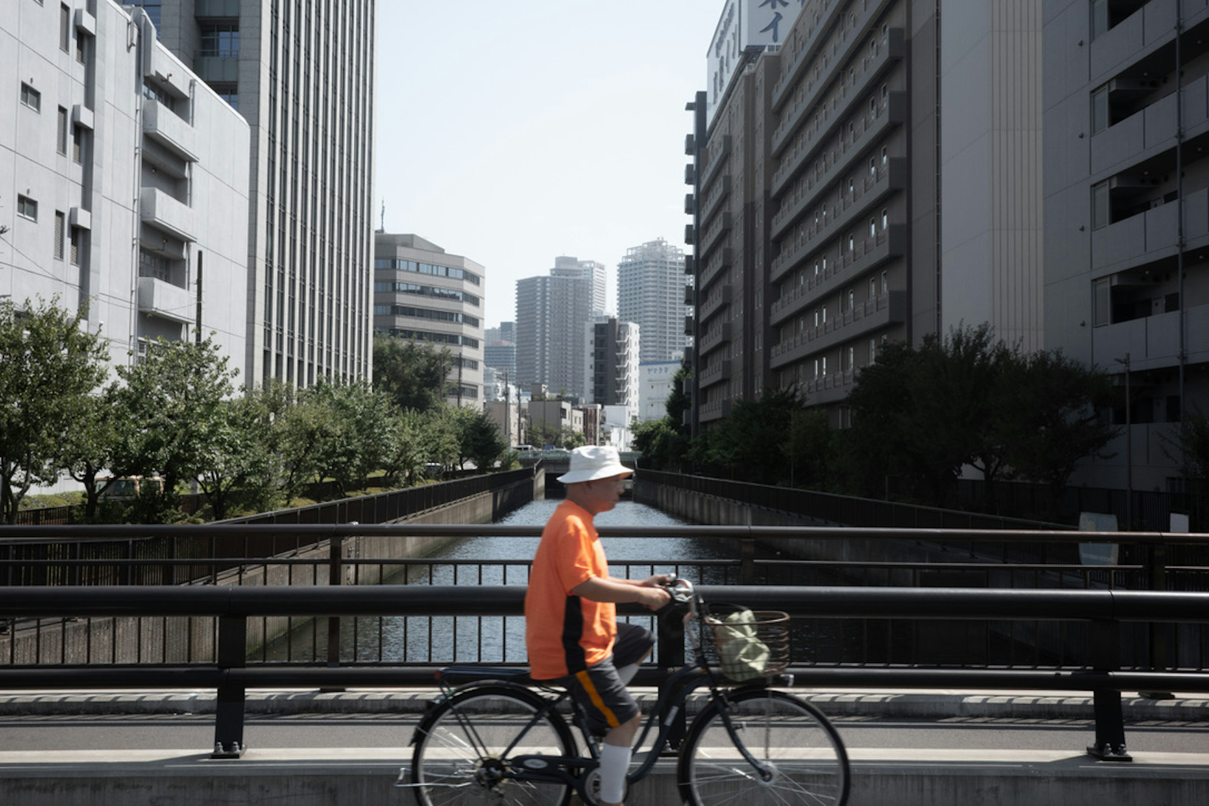 一名男子骑自行车沿着城市运河，周围是建筑物