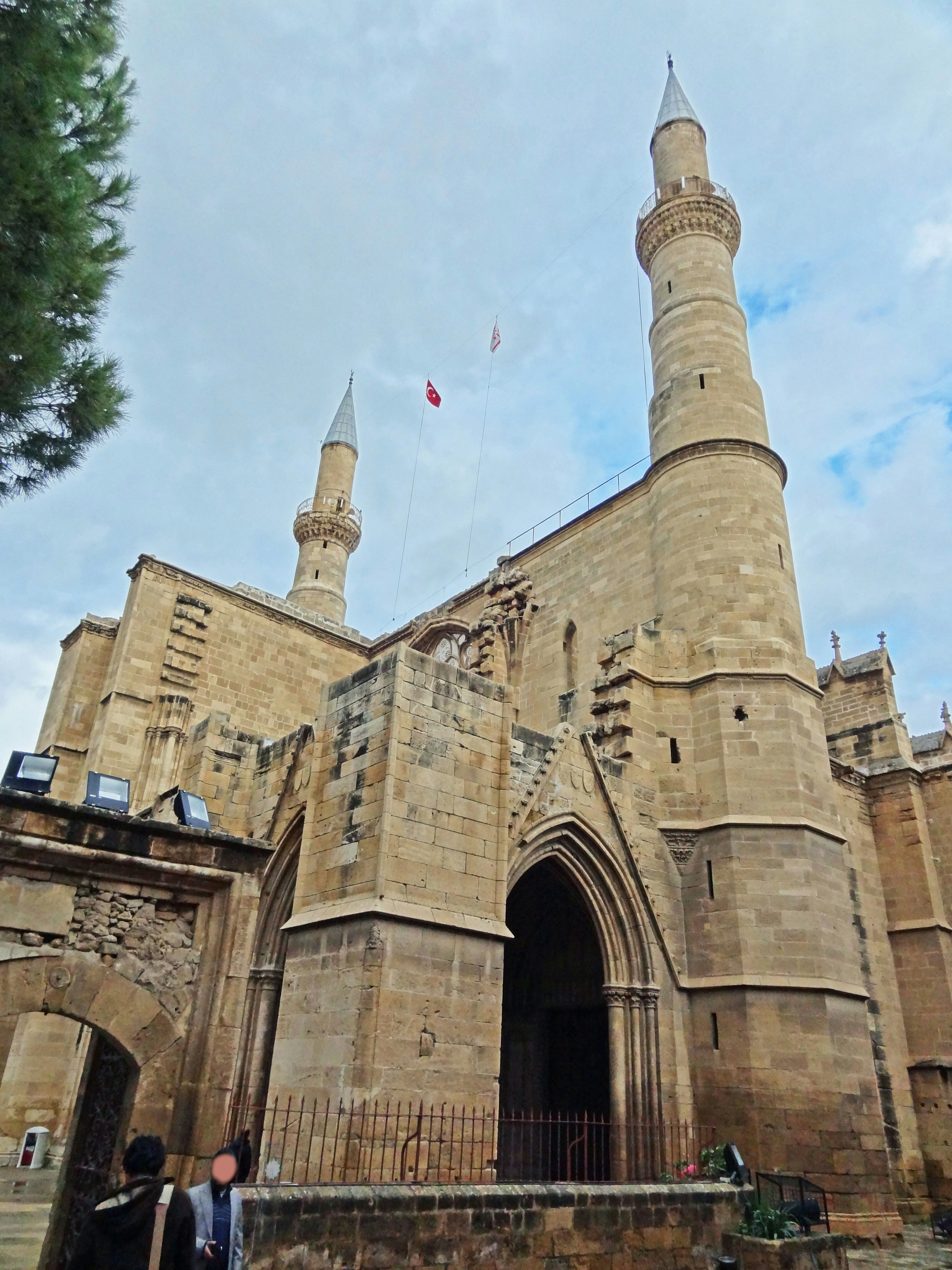 Historic mosque exterior with two minarets stone facade under blue sky