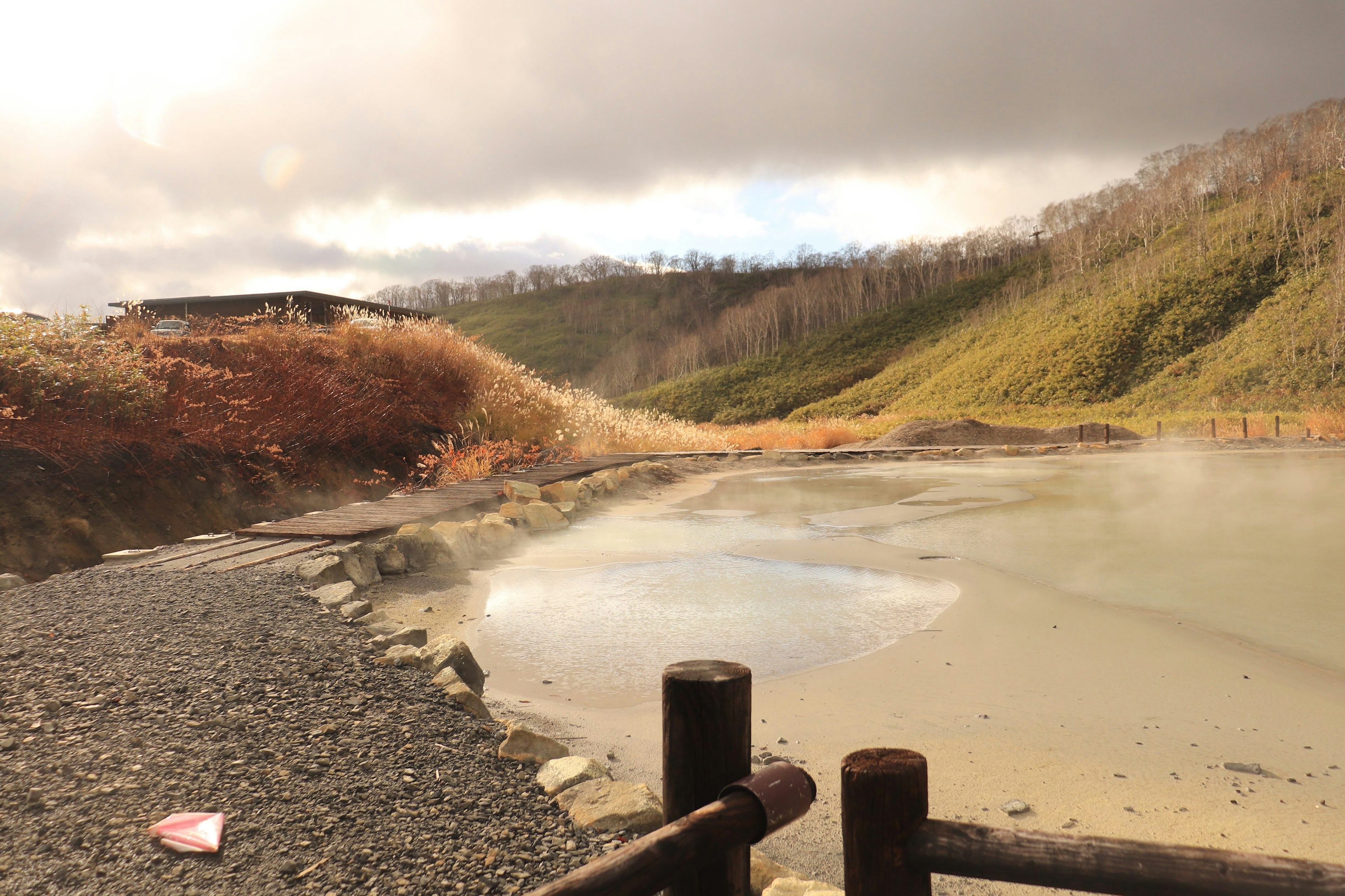 Natural landscape featuring a hot spring with surrounding hills and clouds