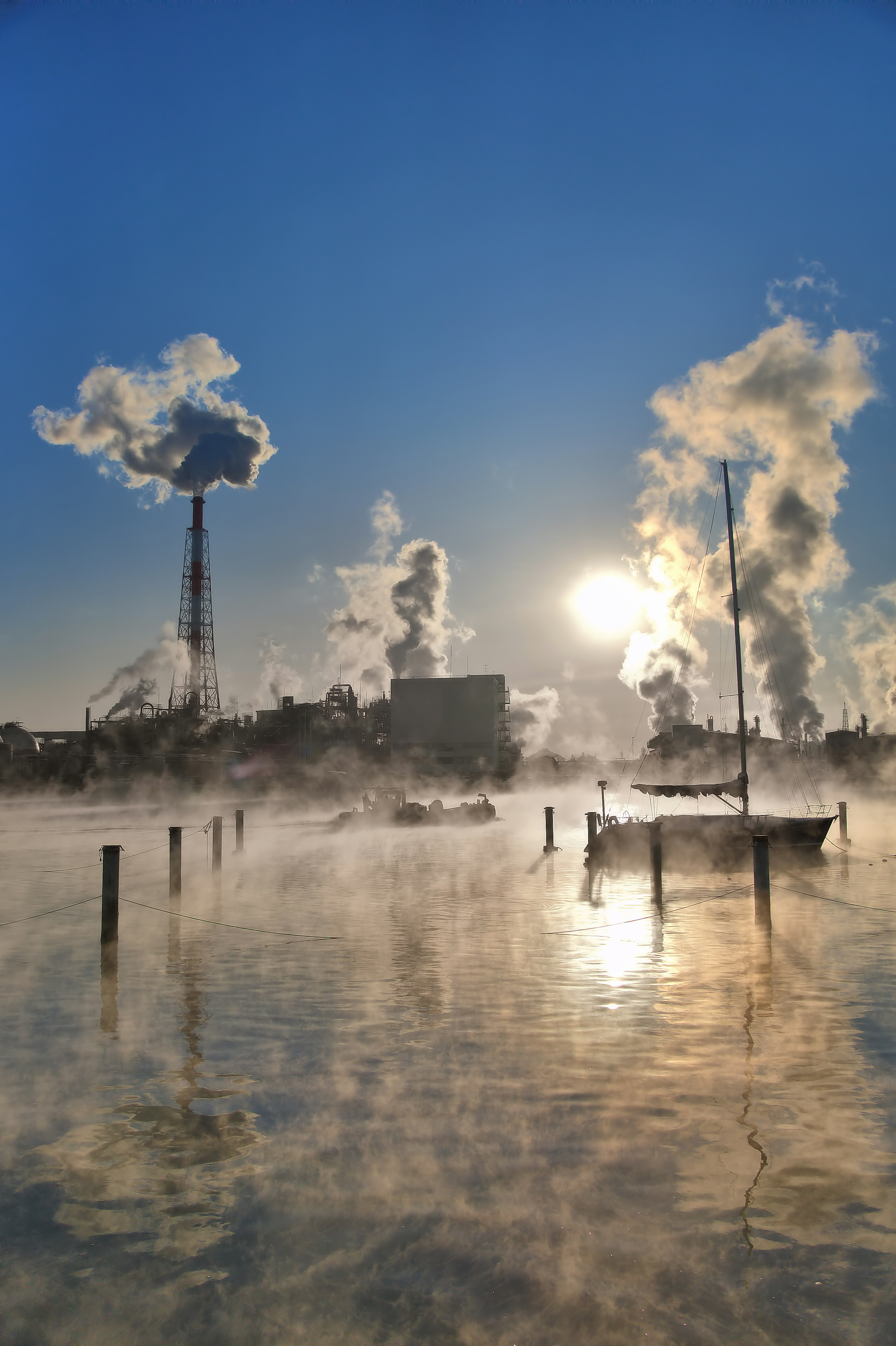 Paysage industriel avec de la vapeur s'élevant et la lumière du soleil se reflétant sur l'eau