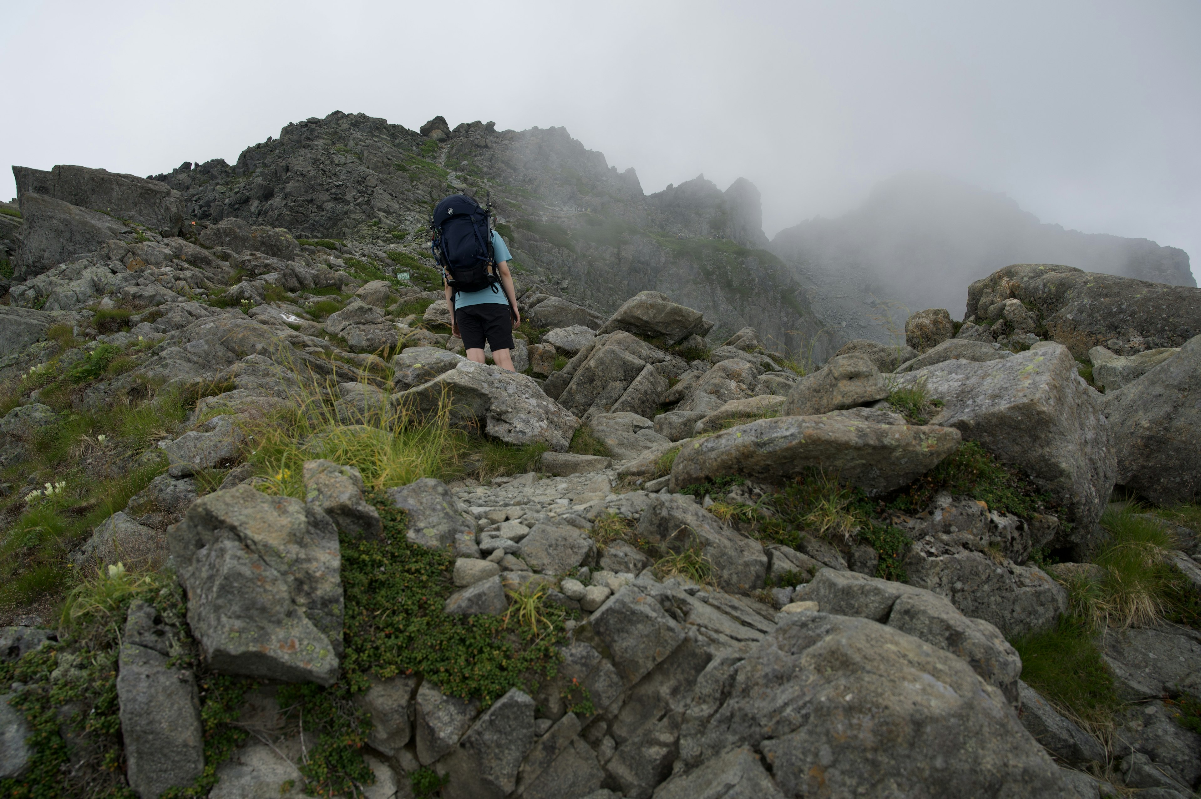 Hiker navigating rocky terrain in foggy conditions