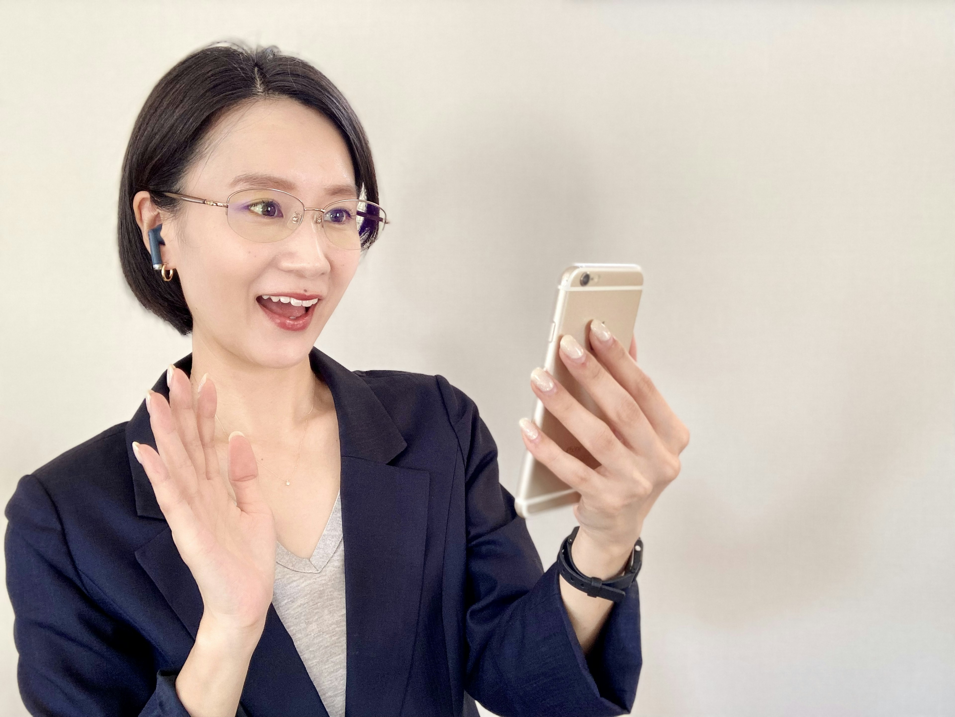 Femme d'affaires souriante faisant signe tout en tenant un smartphone