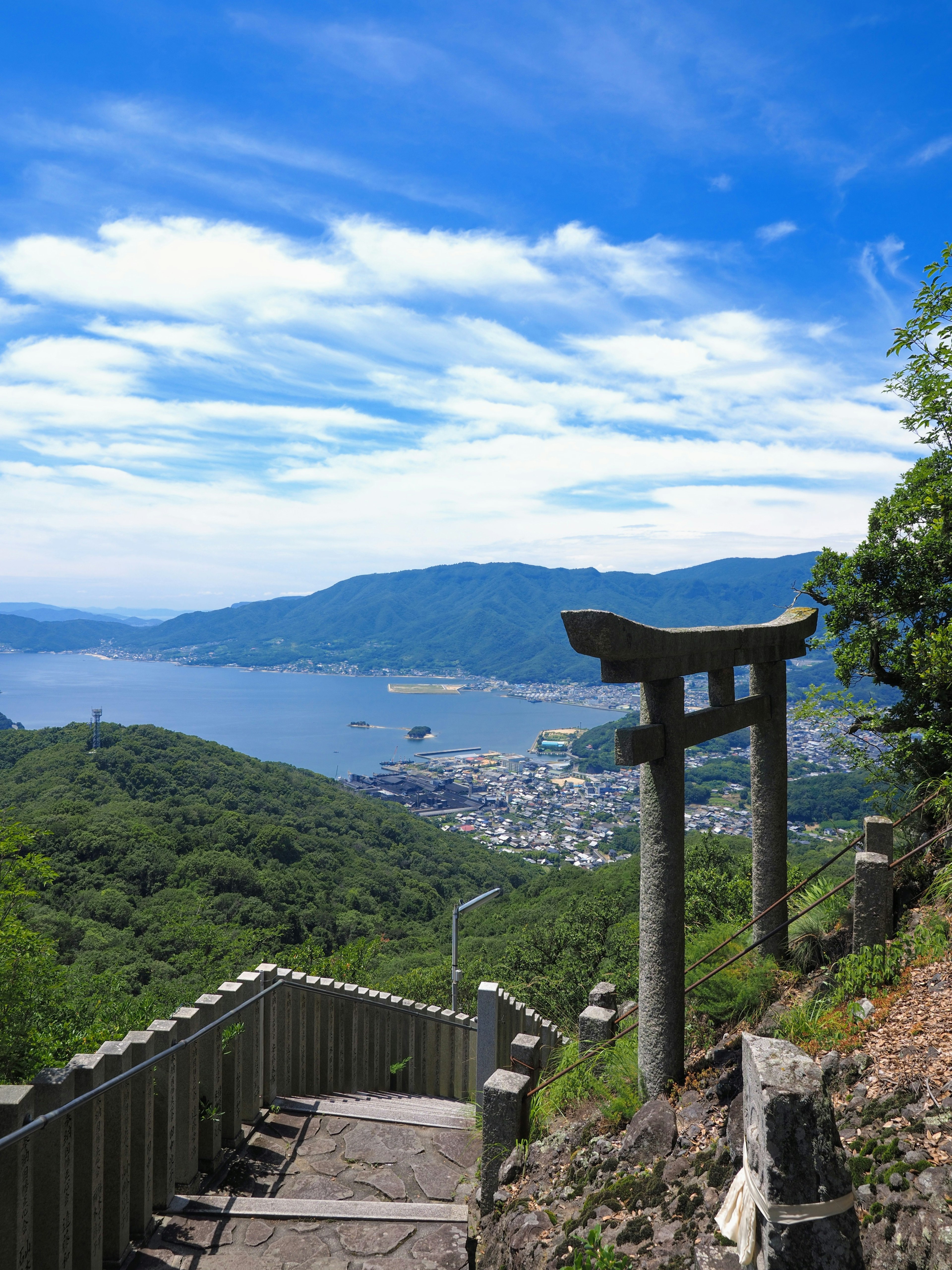 Cổng torii nhìn ra biển và núi dưới bầu trời xanh