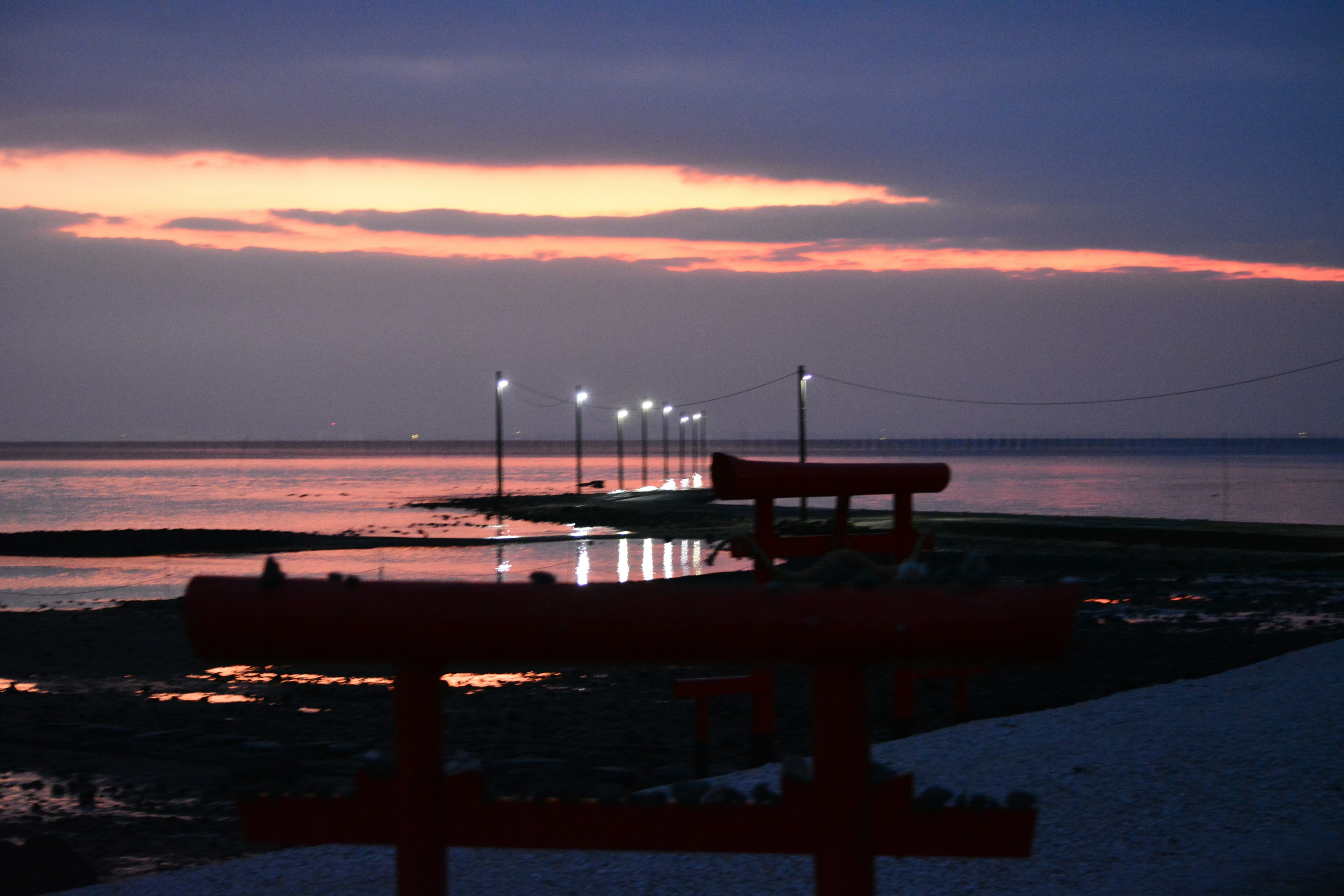 Muelle con faroles al atardecer sobre el mar