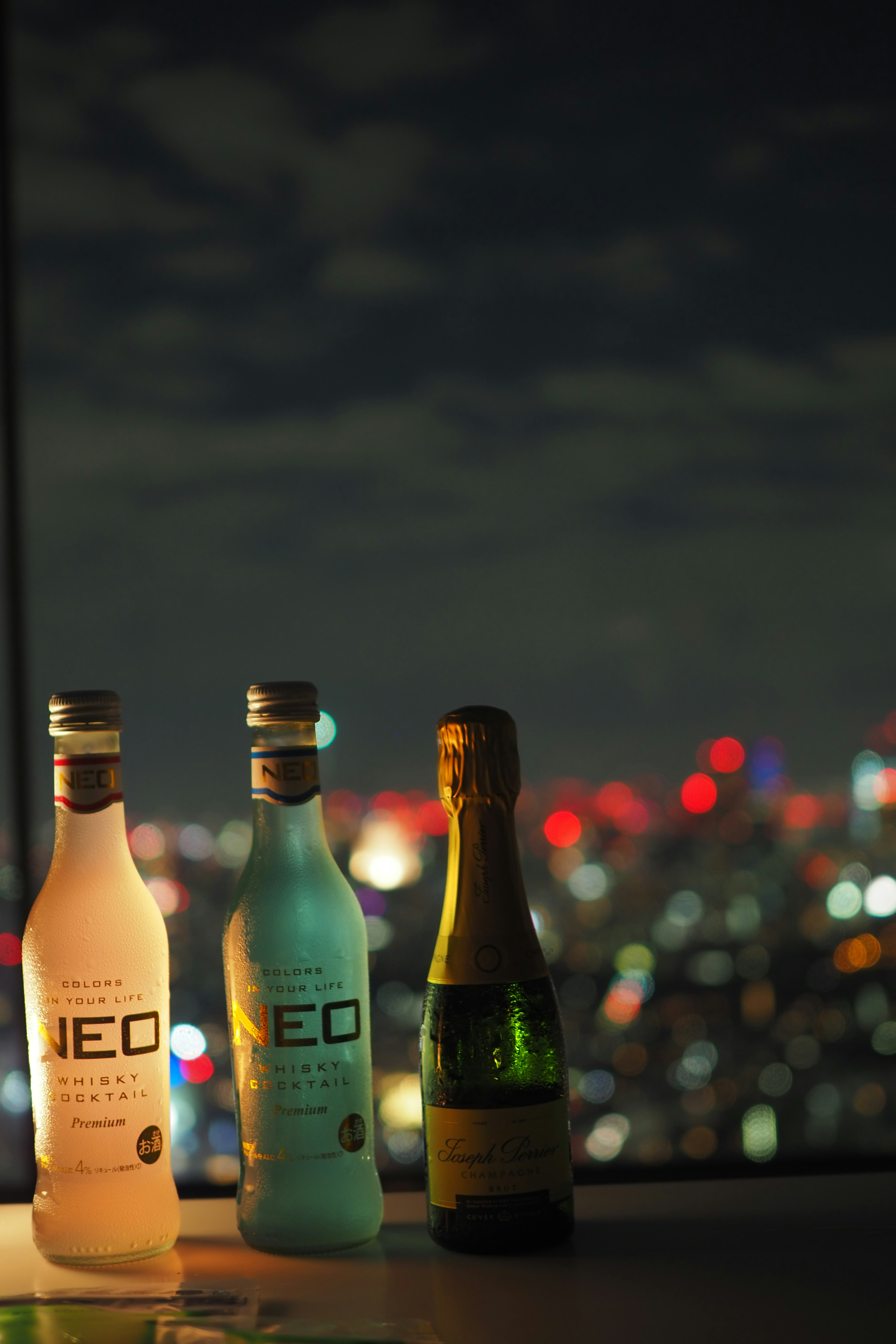 Three bottles of NEO drinks arranged against a night cityscape