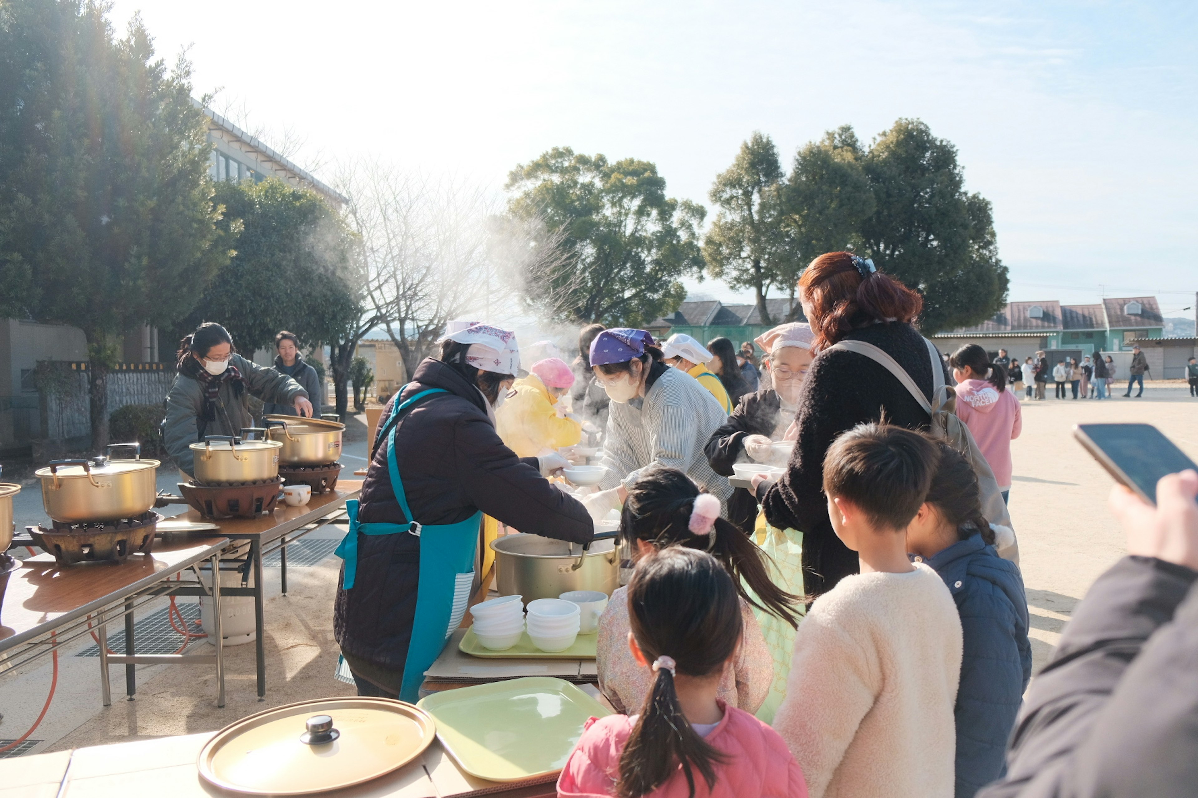 Un evento de cocina comunitaria con adultos y niños preparando comida al aire libre