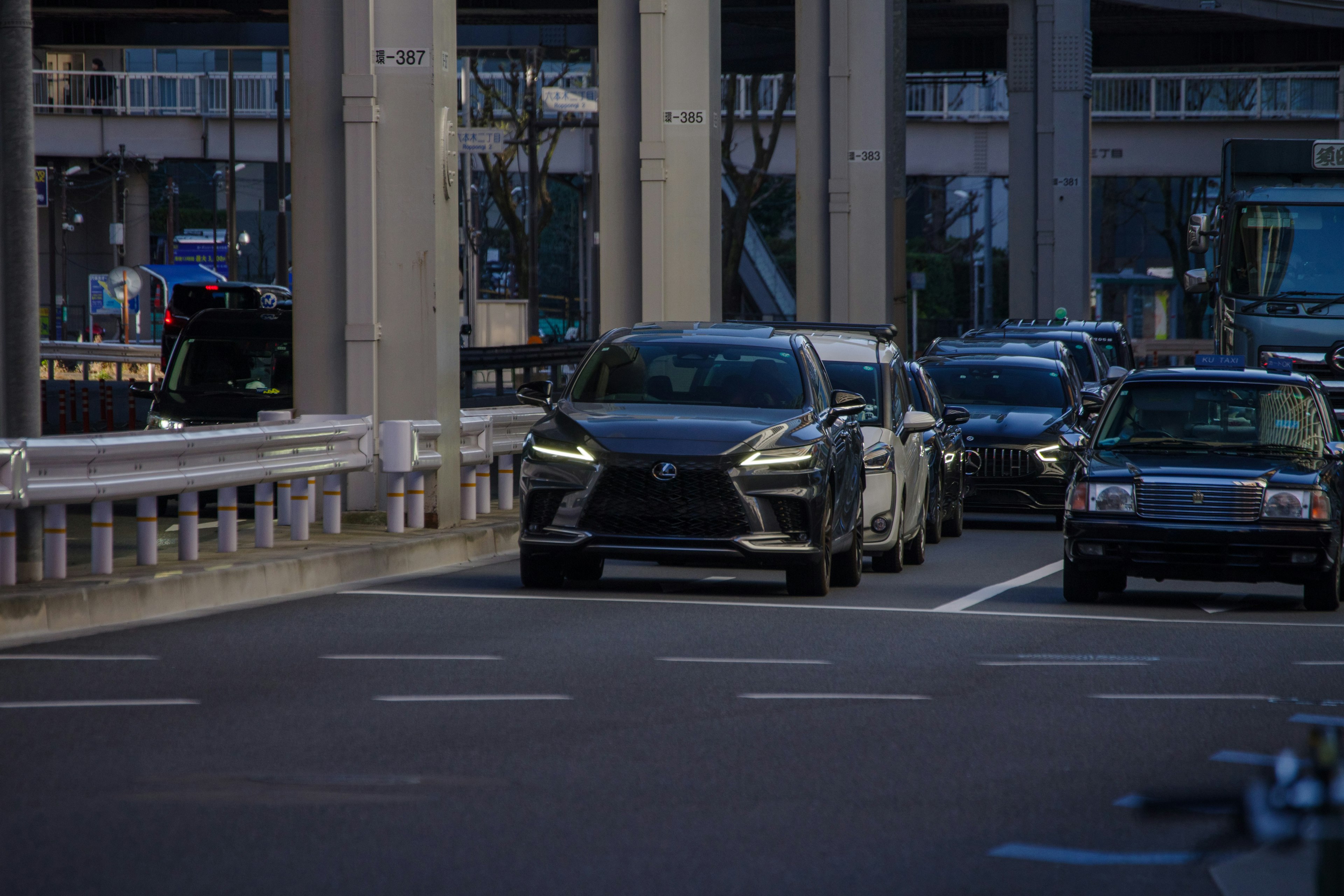 Black car driving on an elevated urban road with surrounding traffic