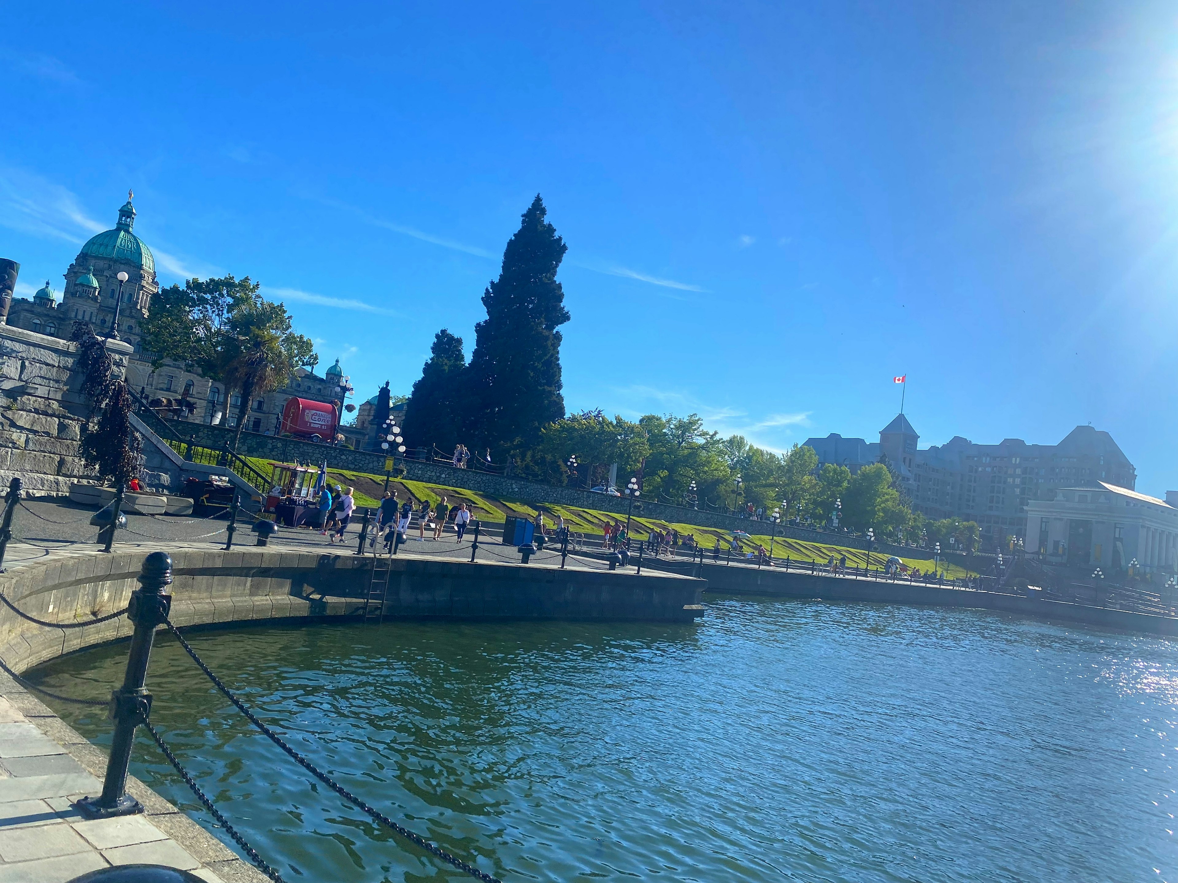 Pemandangan taman dan kolam di bawah langit biru orang-orang berjalan