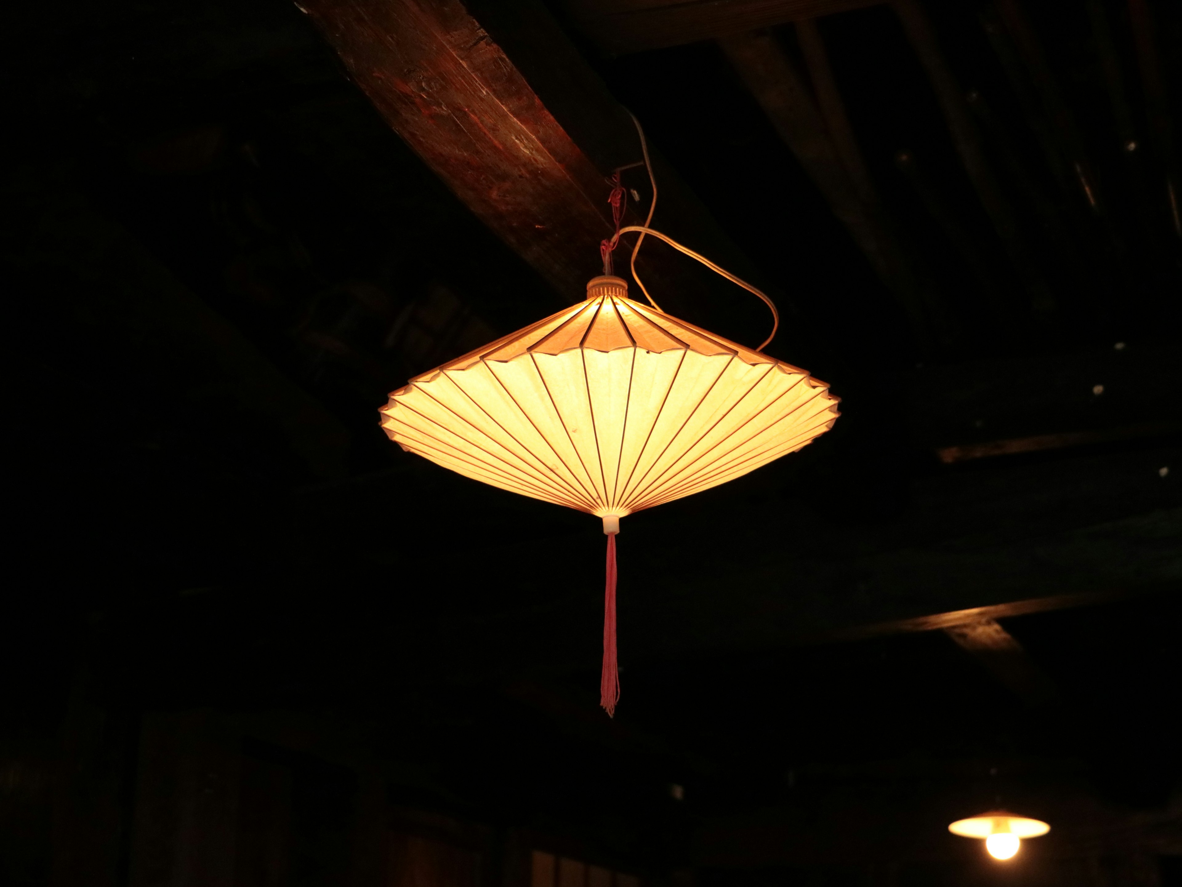 Hanging light fixture shaped like a traditional umbrella emitting soft light