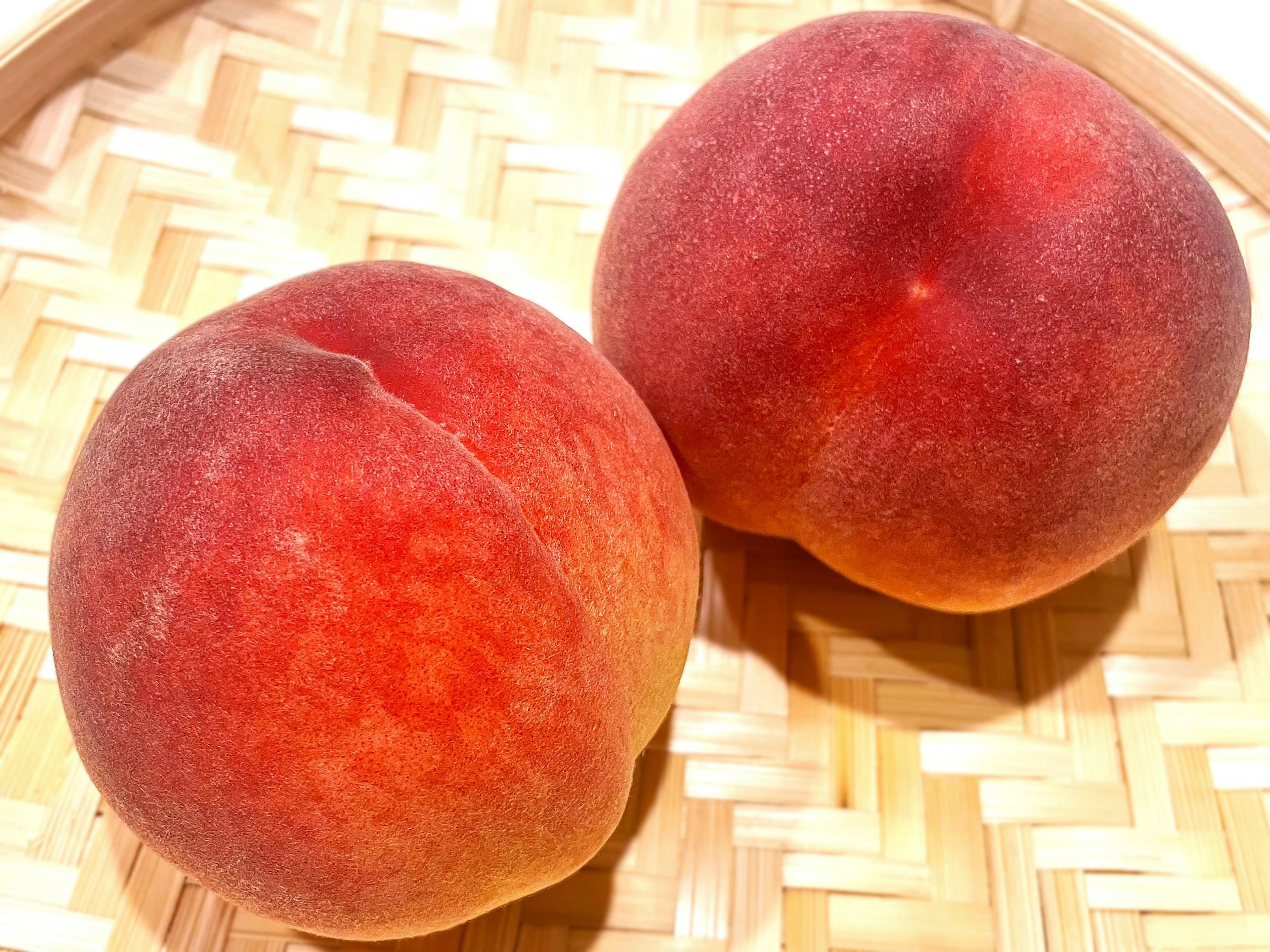 Two ripe peaches placed in a bamboo basket