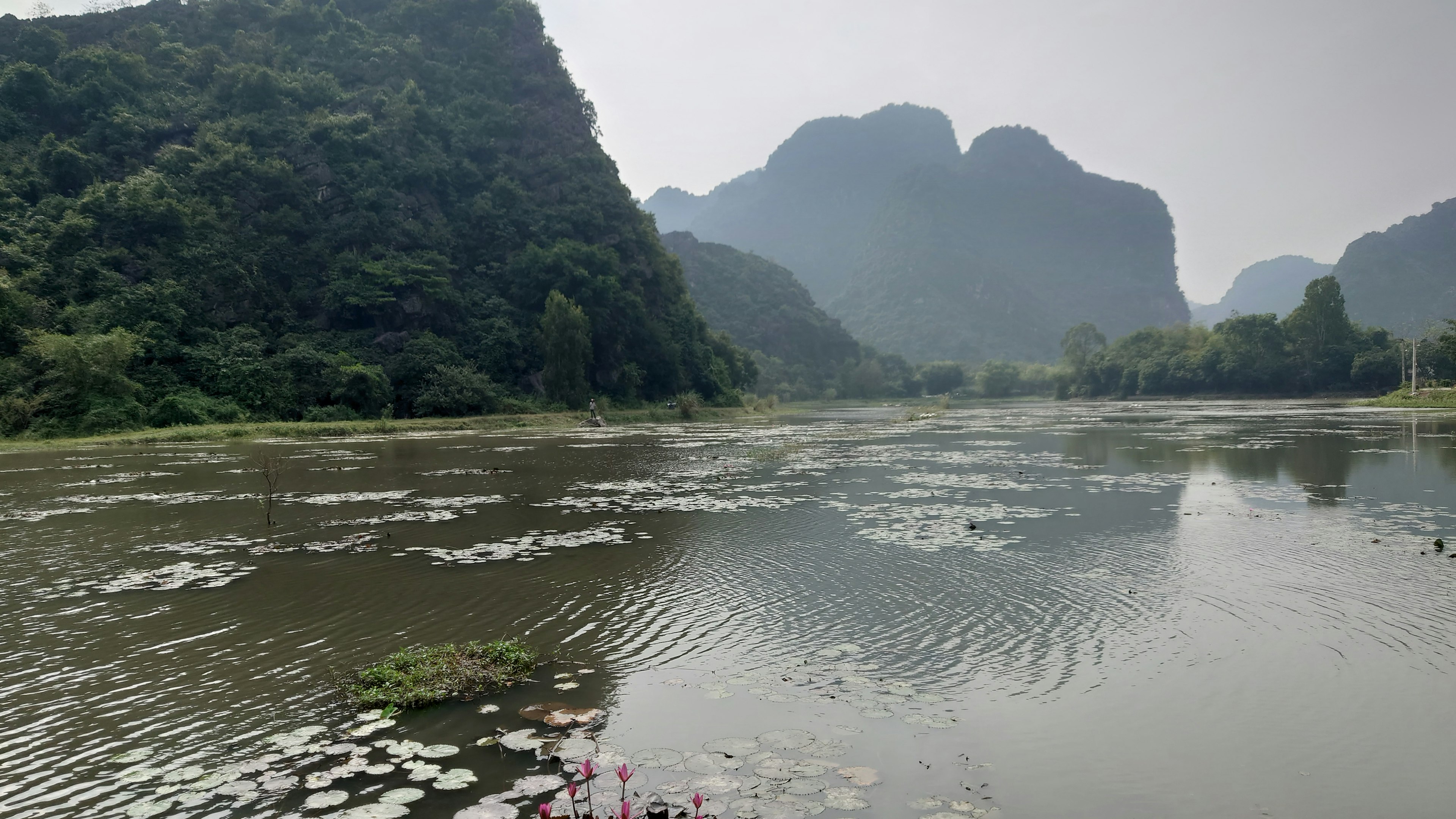 Danau tenang dikelilingi oleh pegunungan hijau