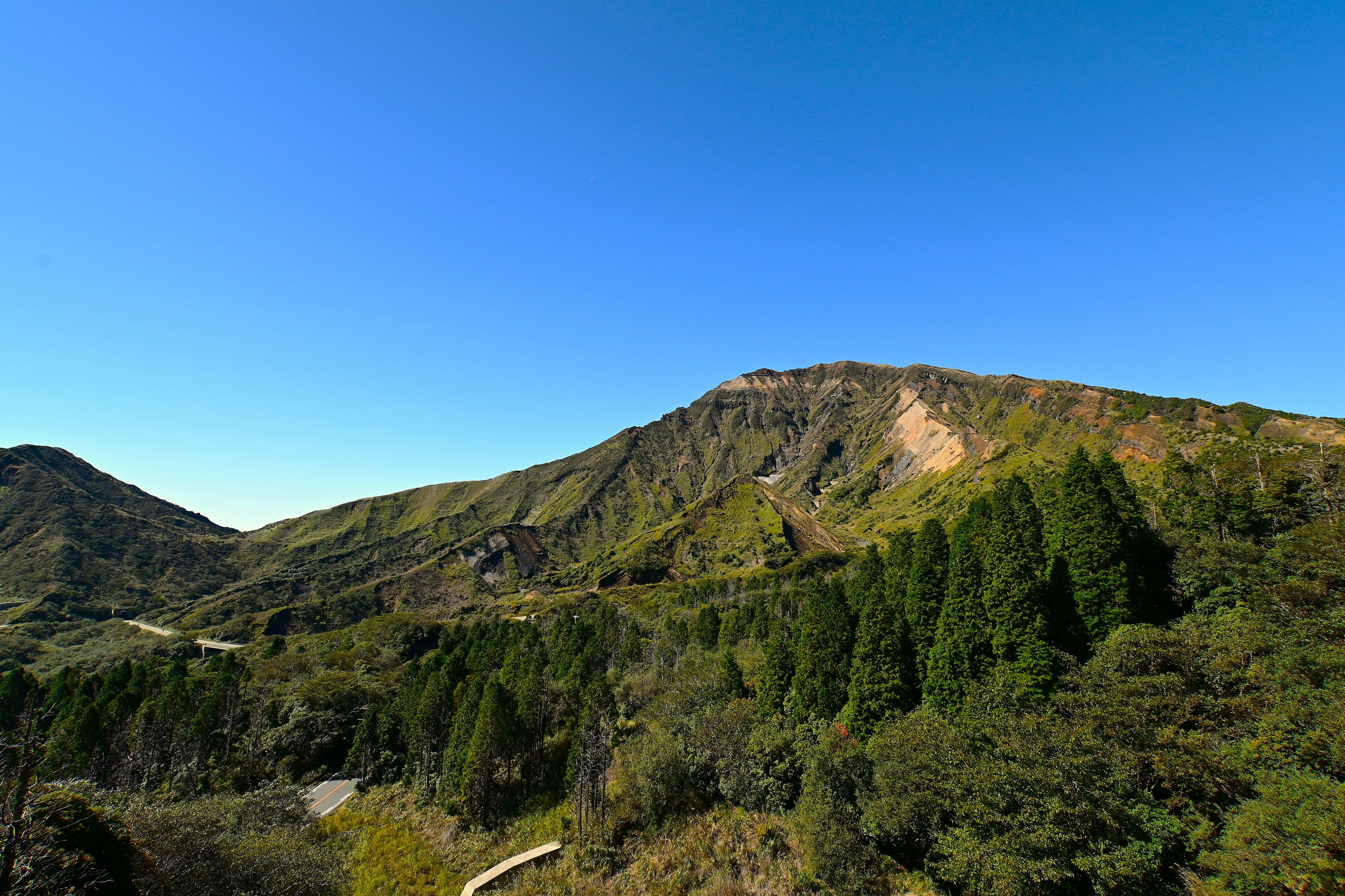 Scenic view of lush green mountains and hills under a clear blue sky