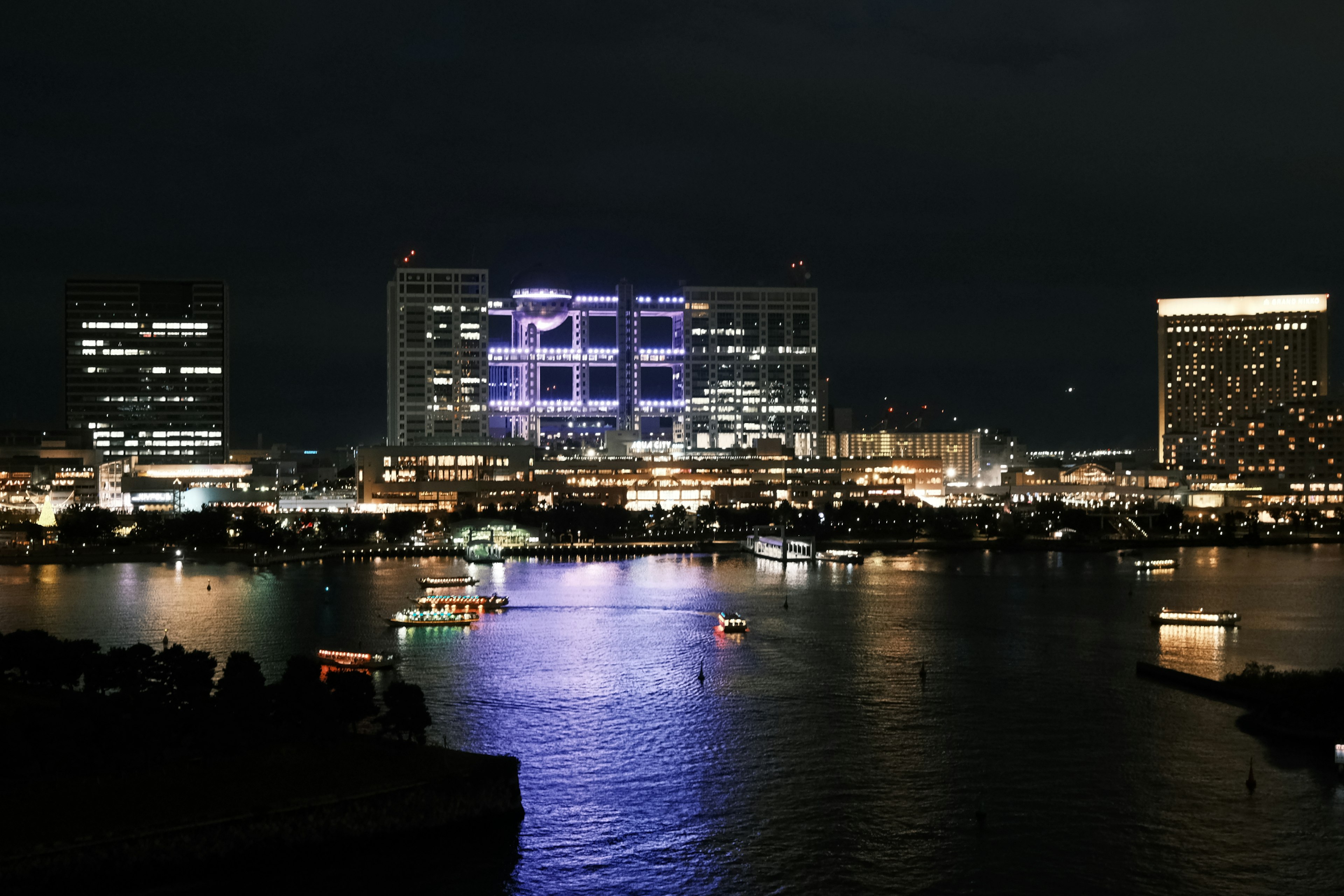 Paisaje urbano nocturno con edificios iluminados y reflejos en el agua