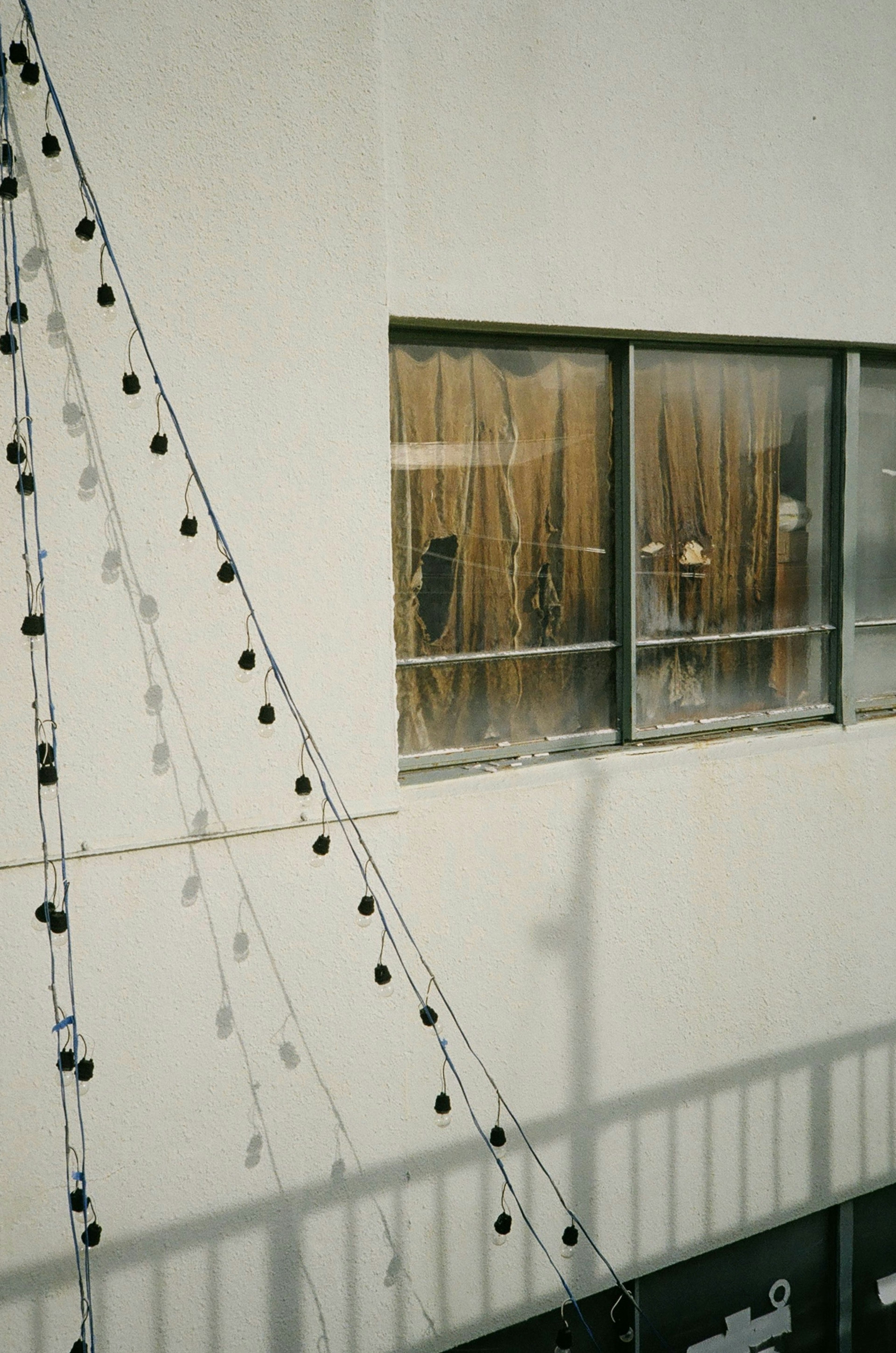 Decorative black lights on a white wall with an indoor view through curtains