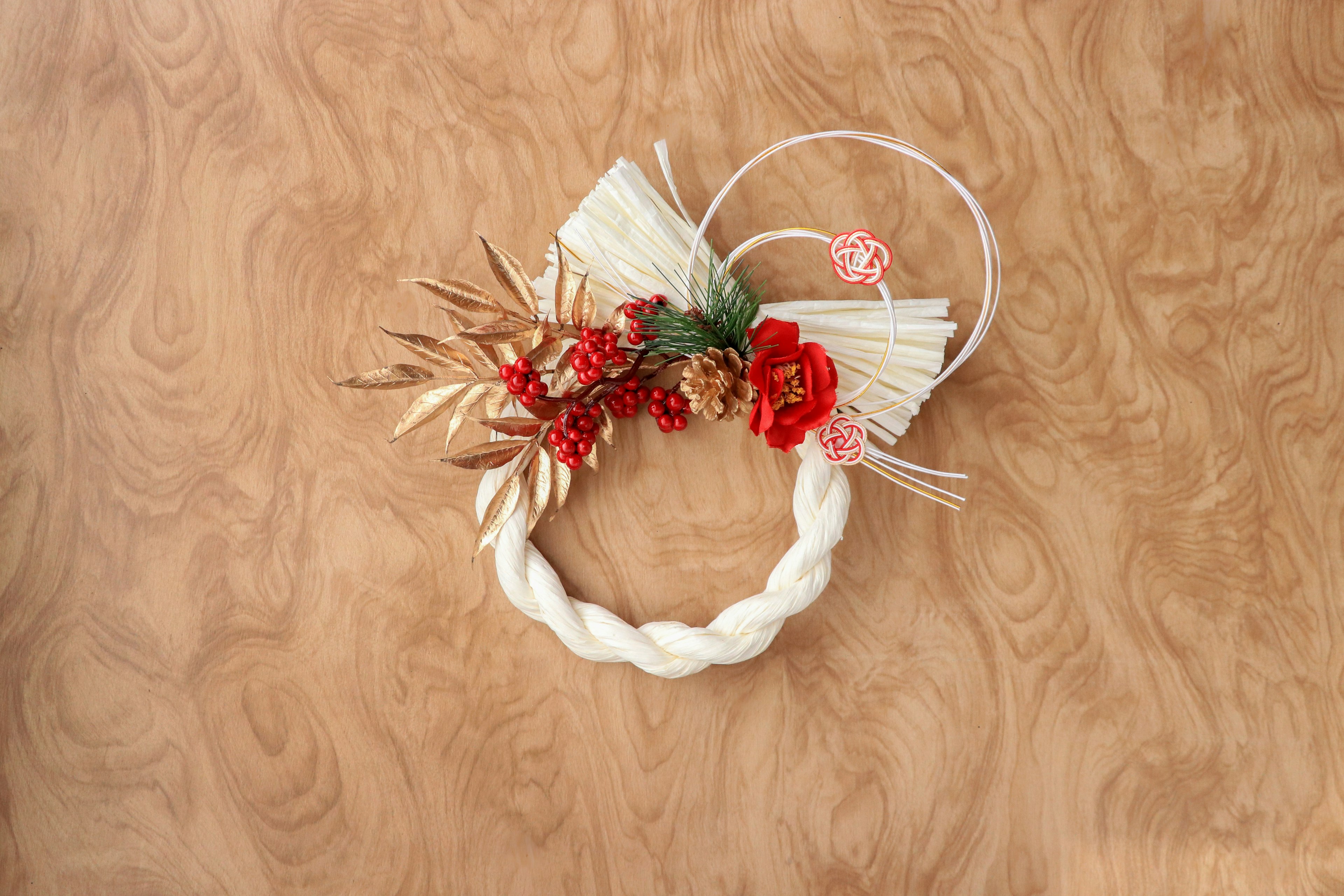 Une couronne tressée blanche ornée de fleurs rouges et de décorations en herbe séchée