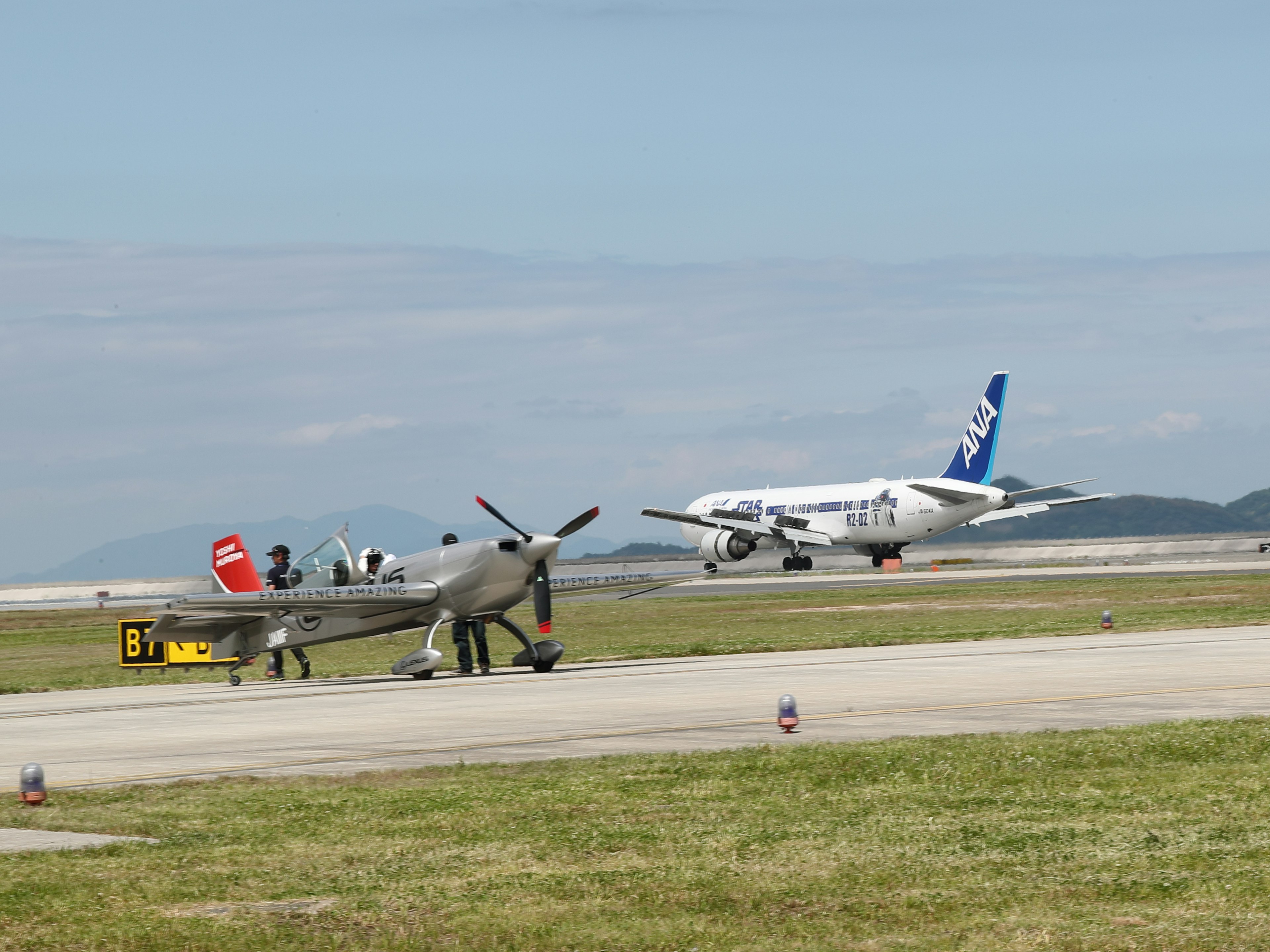 Vintage fighter aircraft on runway with modern passenger jet taking off