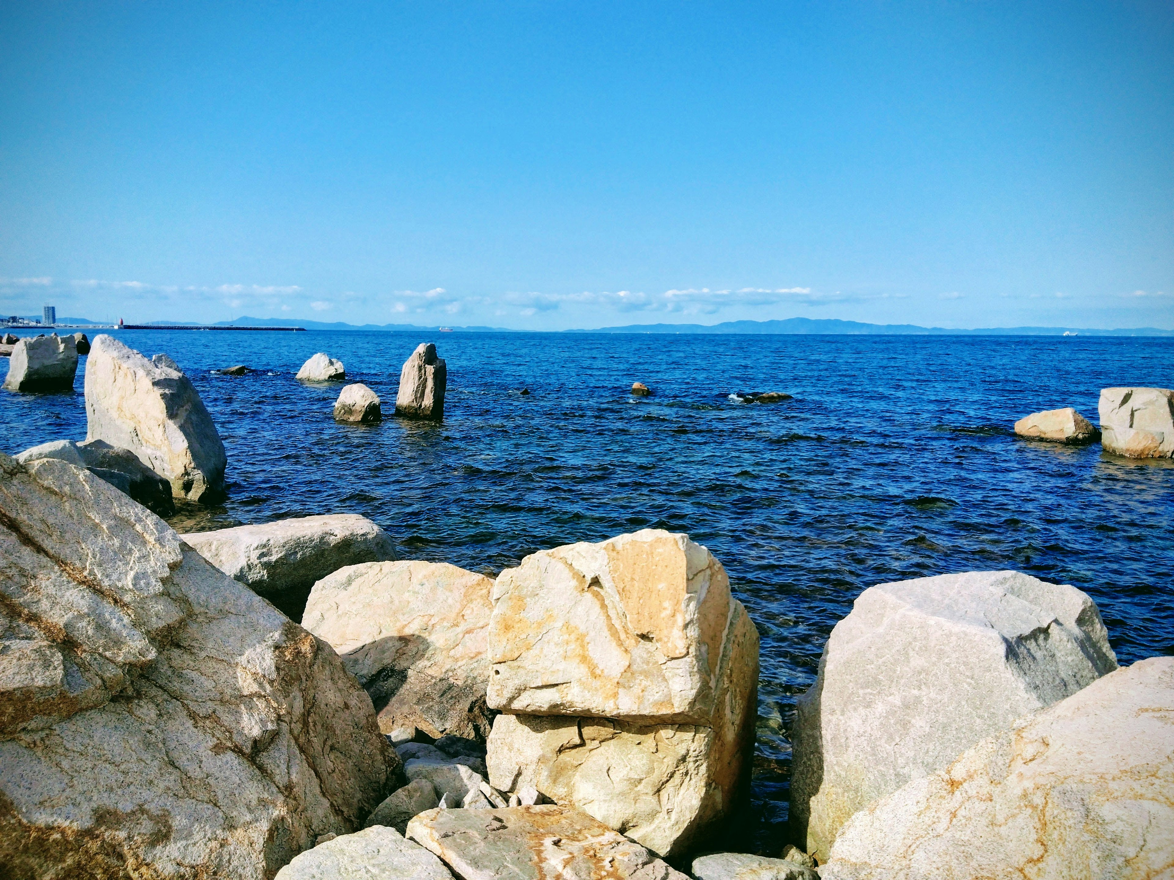 Scenic view of the sea with large rocks and a clear blue sky