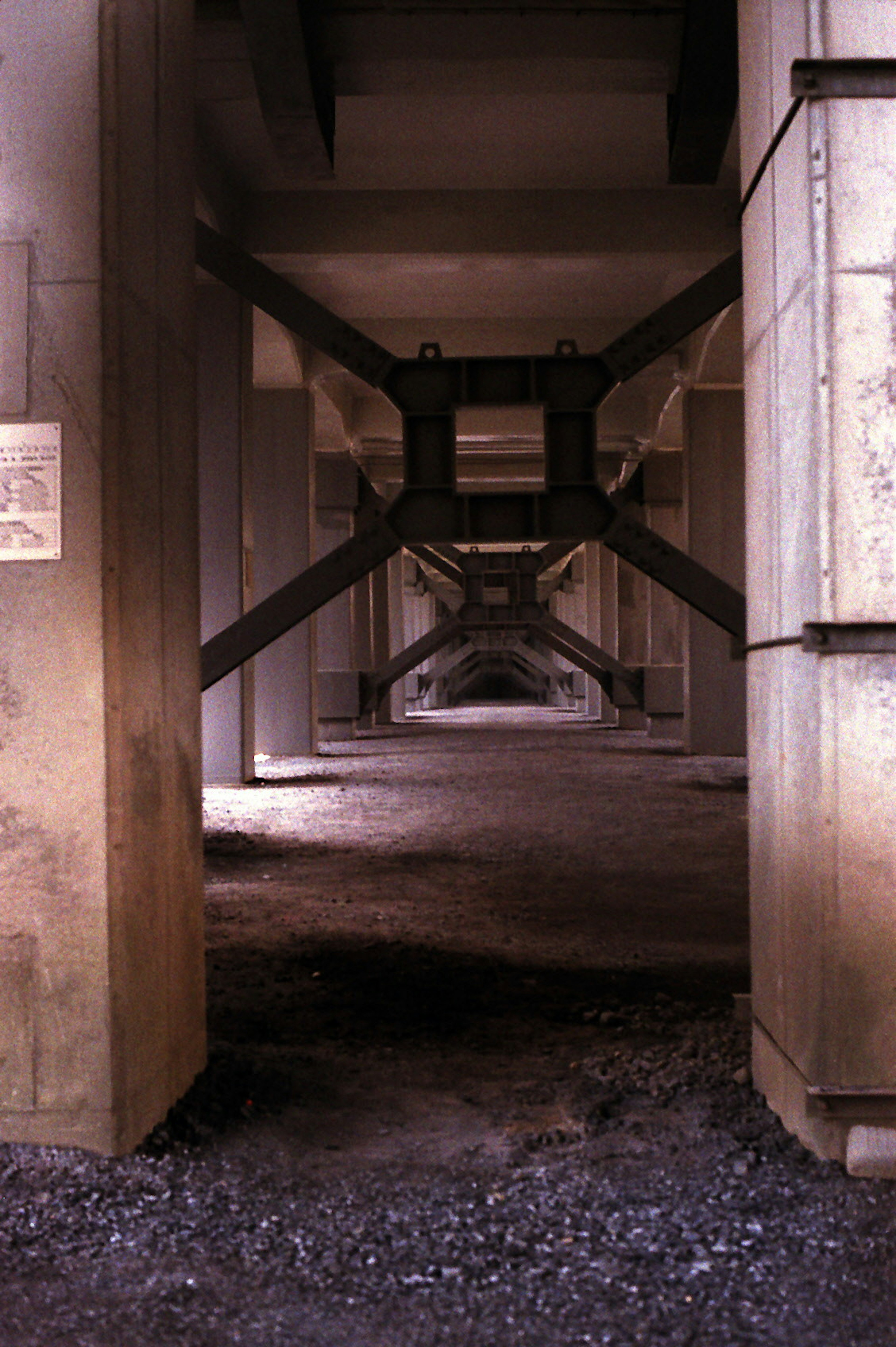 Concrete and metal structures under a bridge creating a symmetrical perspective