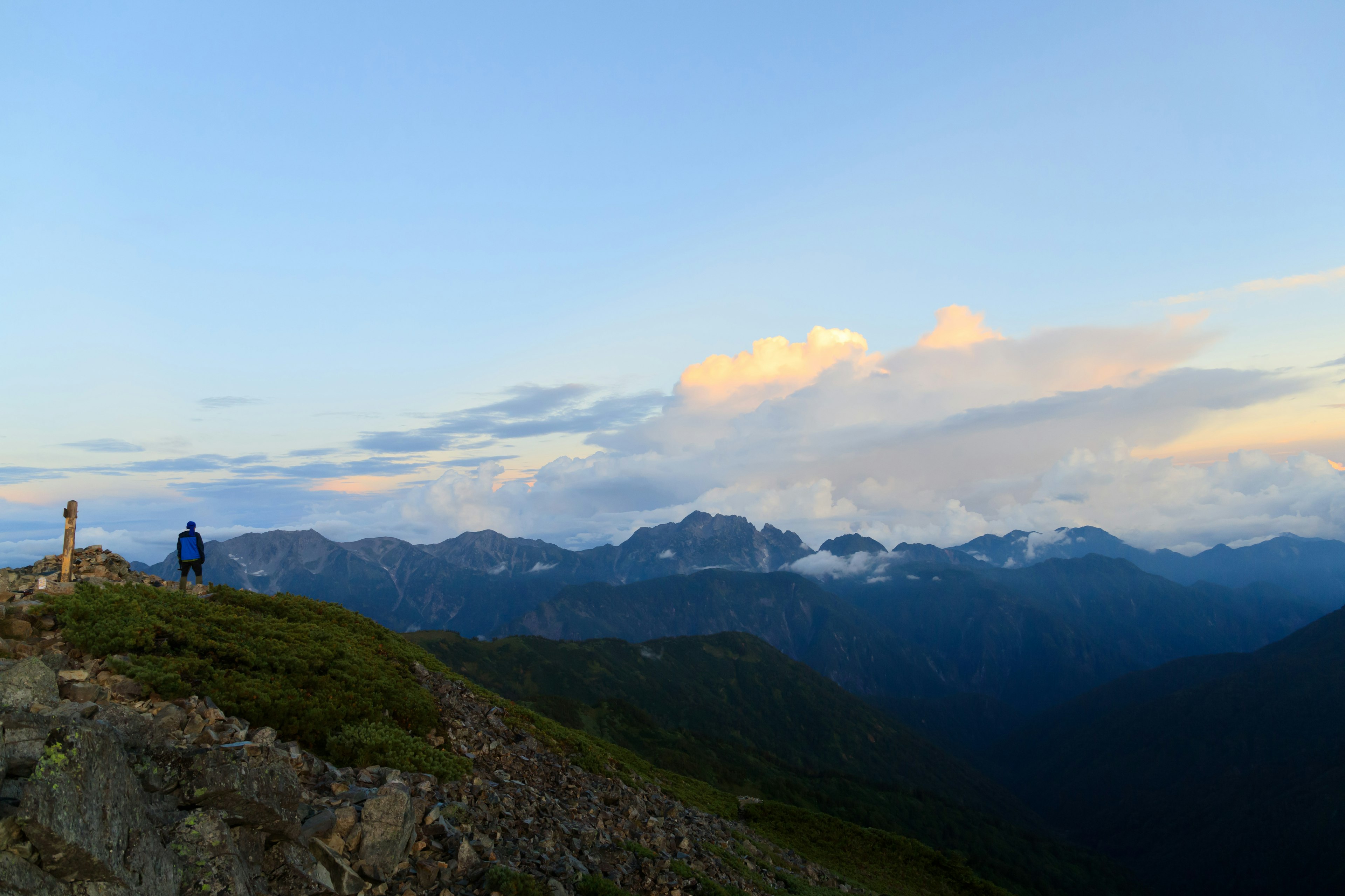 在藍天和雲彩下站在山脊上的徒步旅行者