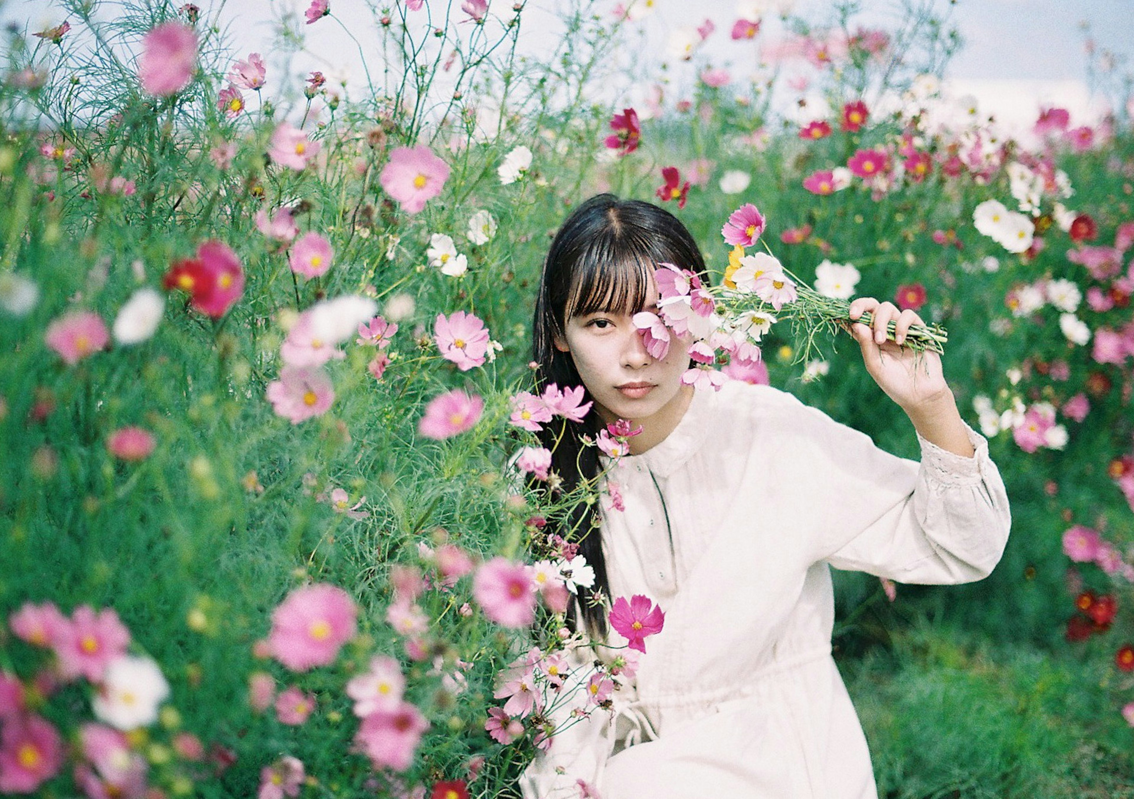 Retrato de una mujer rodeada de flores que lleva un vestido de color claro