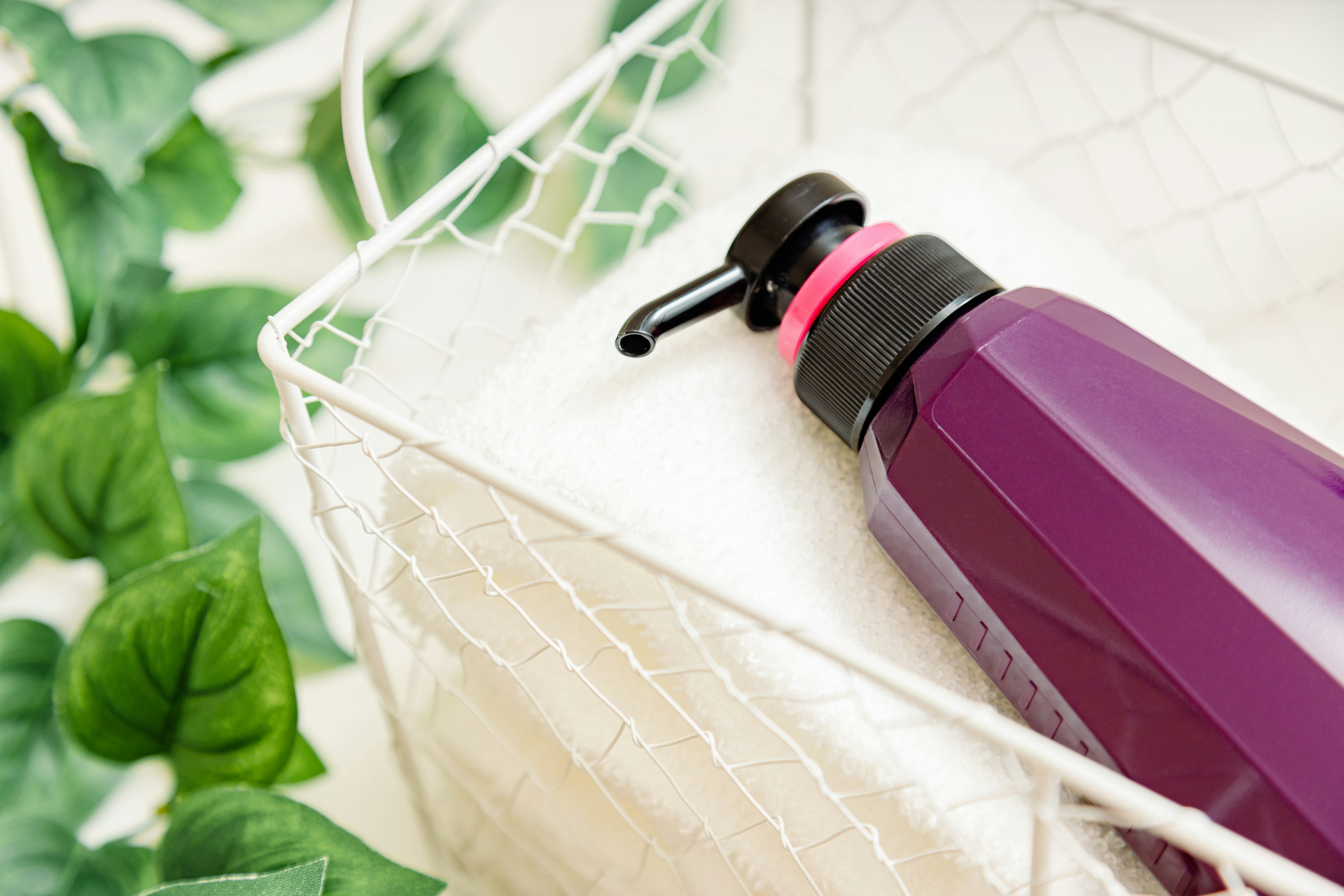 Purple bottle and white towel in a wire basket