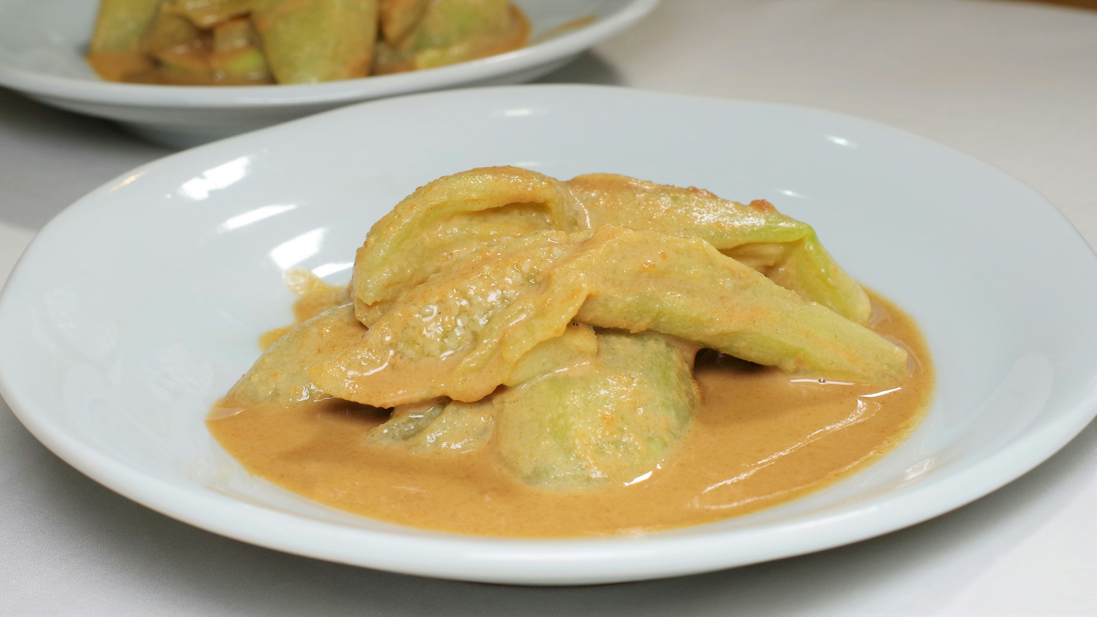 Ravioli coperti da una salsa cremosa serviti in un piatto bianco