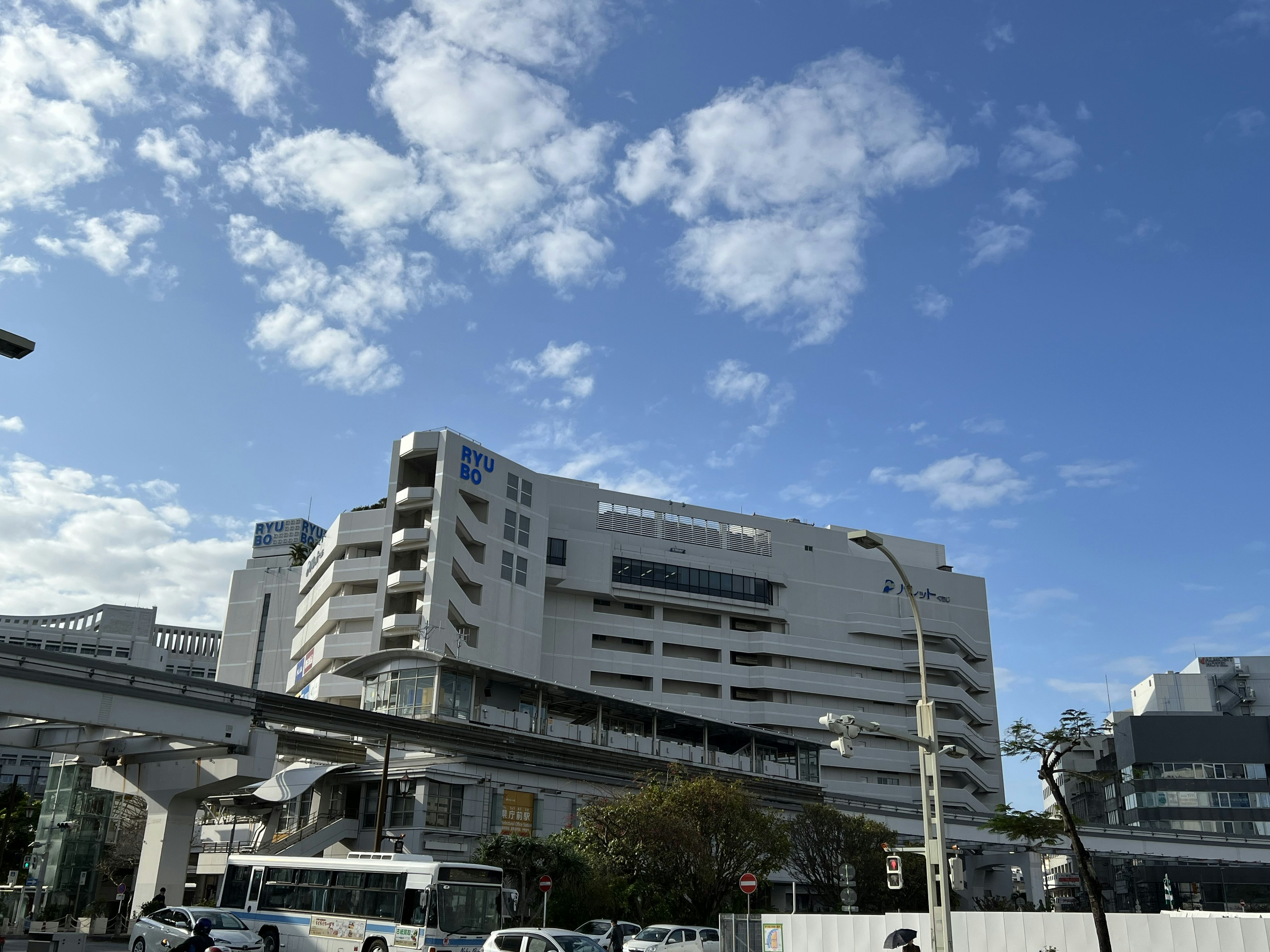 Edificio moderno bajo un cielo azul con nubes y monorraíl