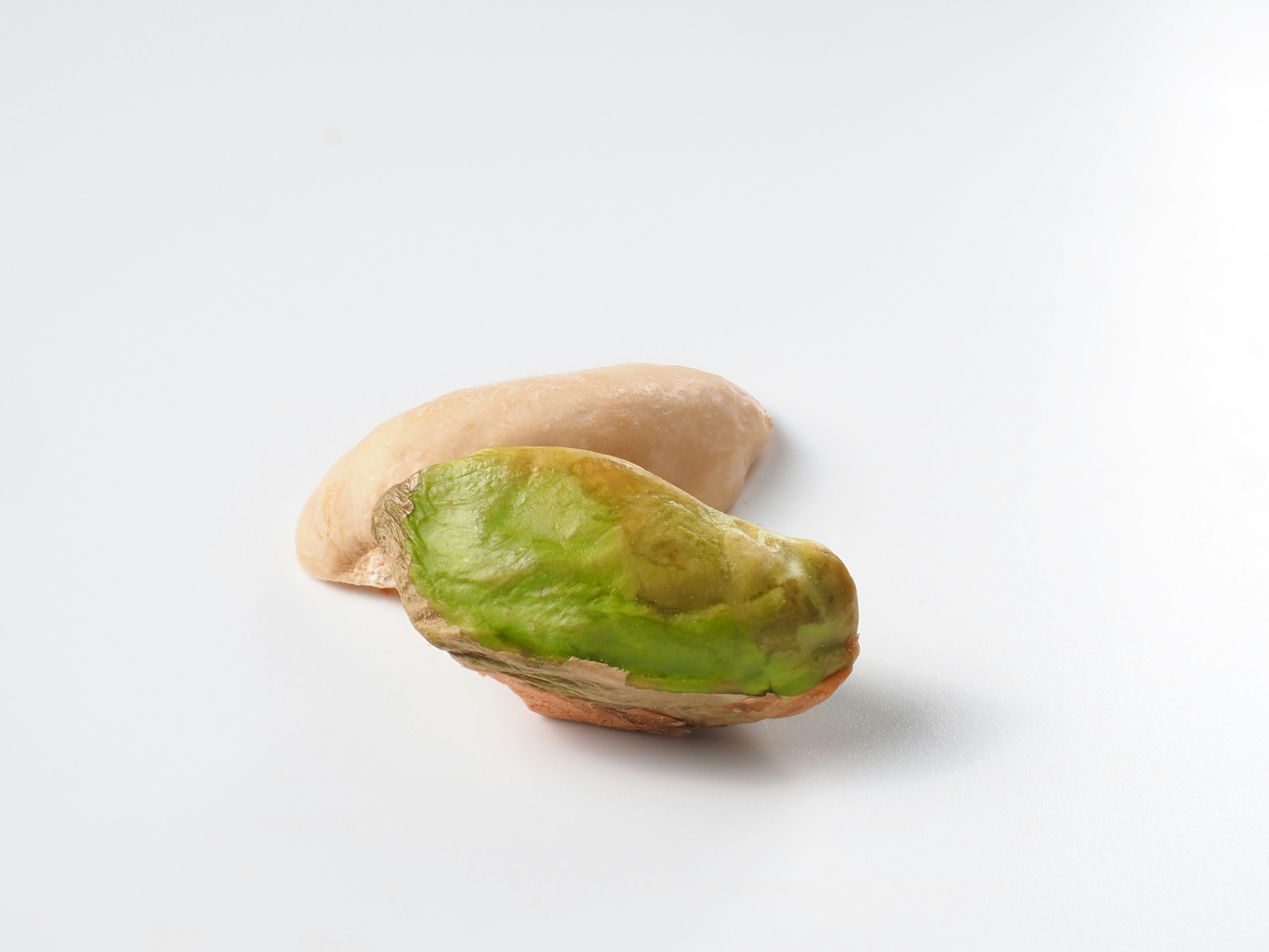 Two nuts in green and cream colors placed on a white background