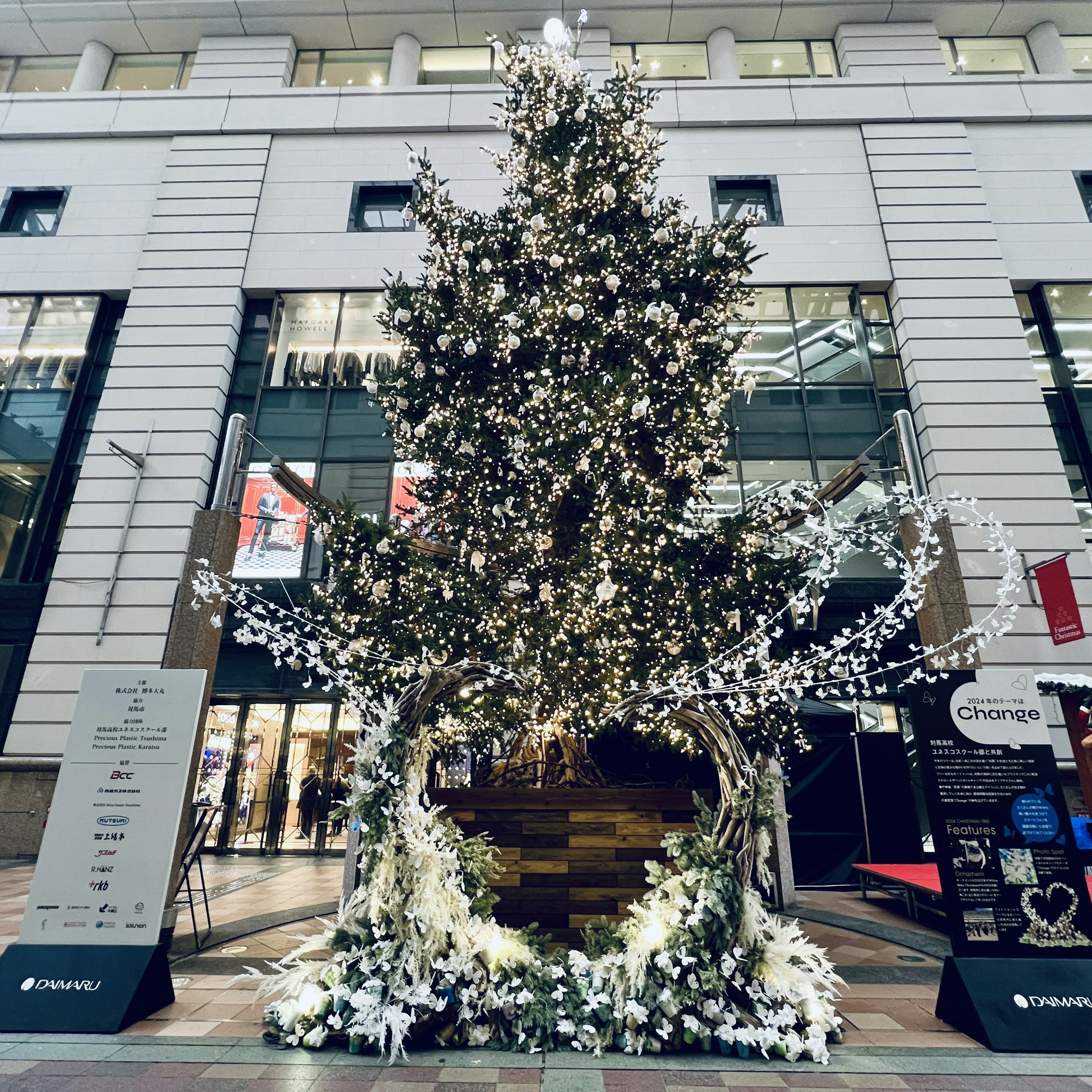 Árbol de Navidad adornado con flores blancas y decoración de arco en un espacio comercial