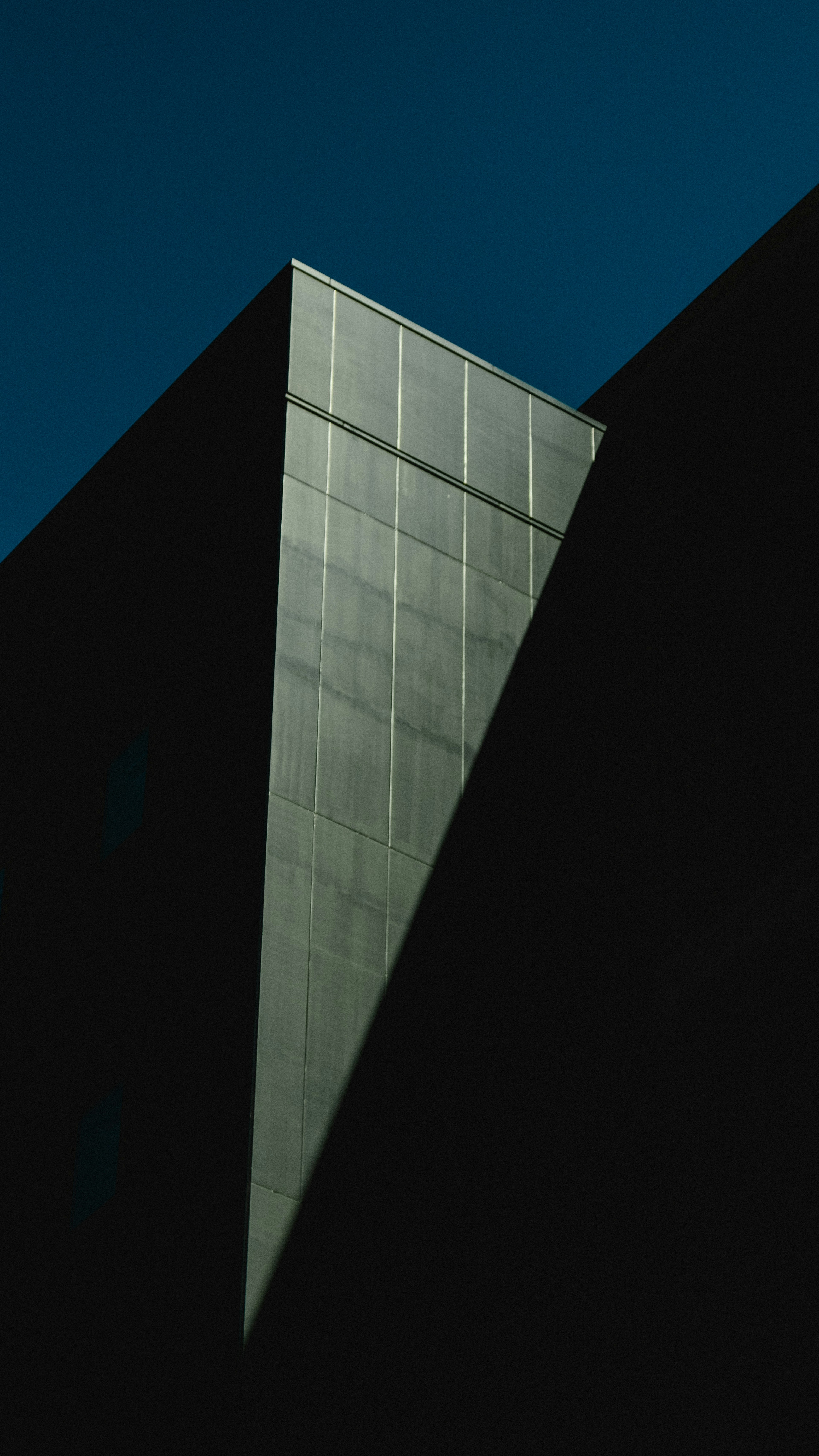 A sharp angled section of a building against a dark background