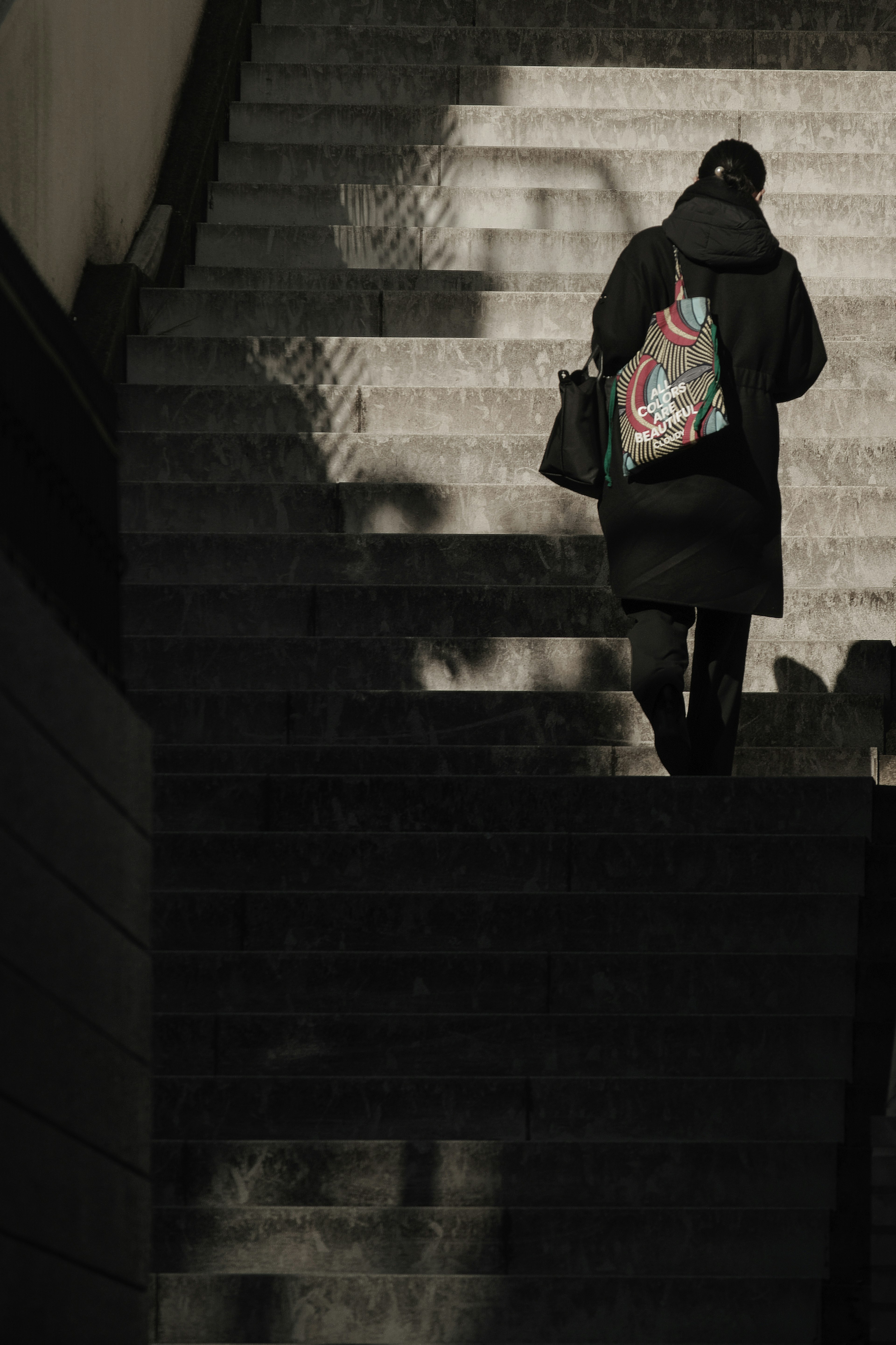 Persona subiendo escaleras con sombras contrastantes