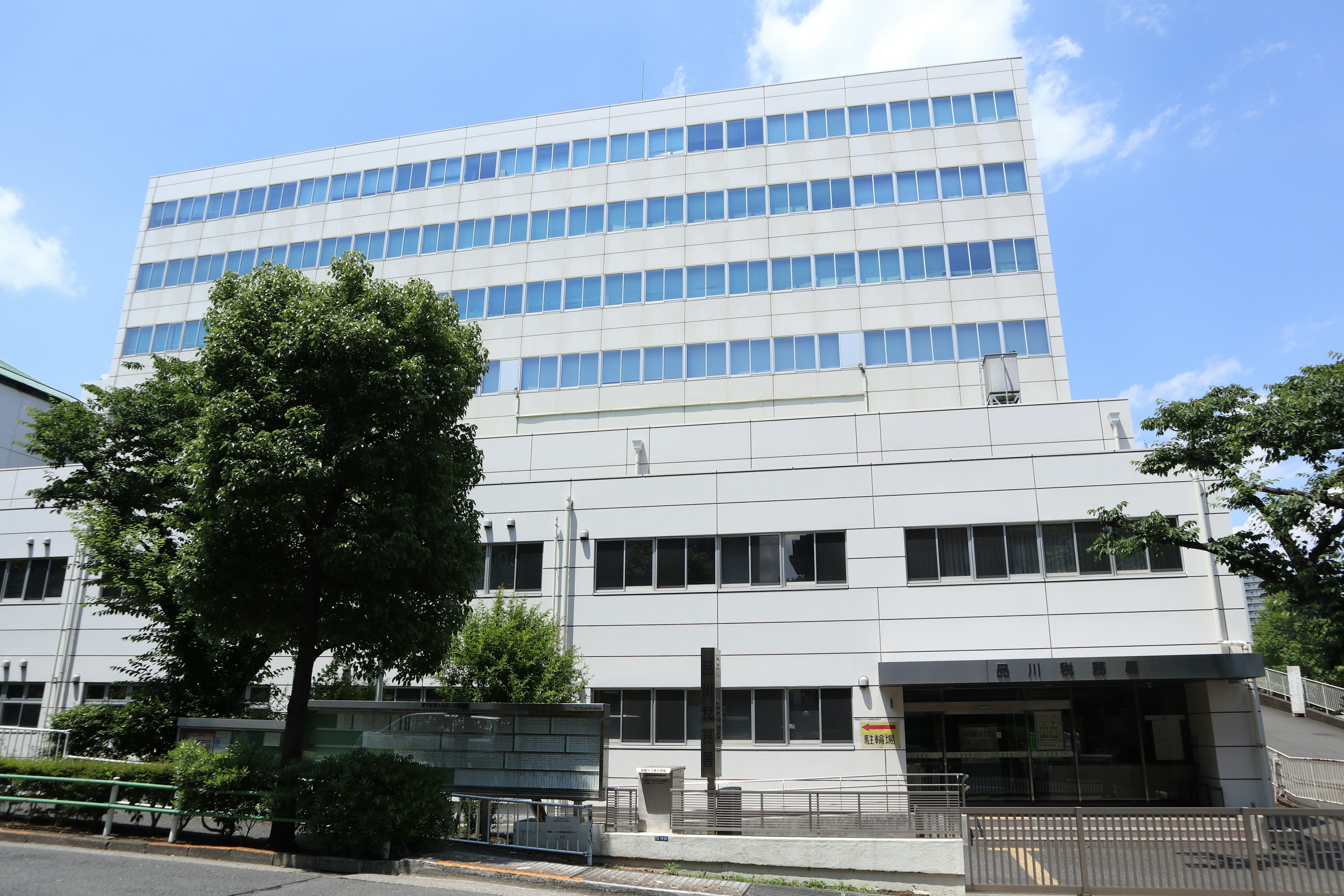 Edificio bianco con grandi finestre e vegetazione circostante