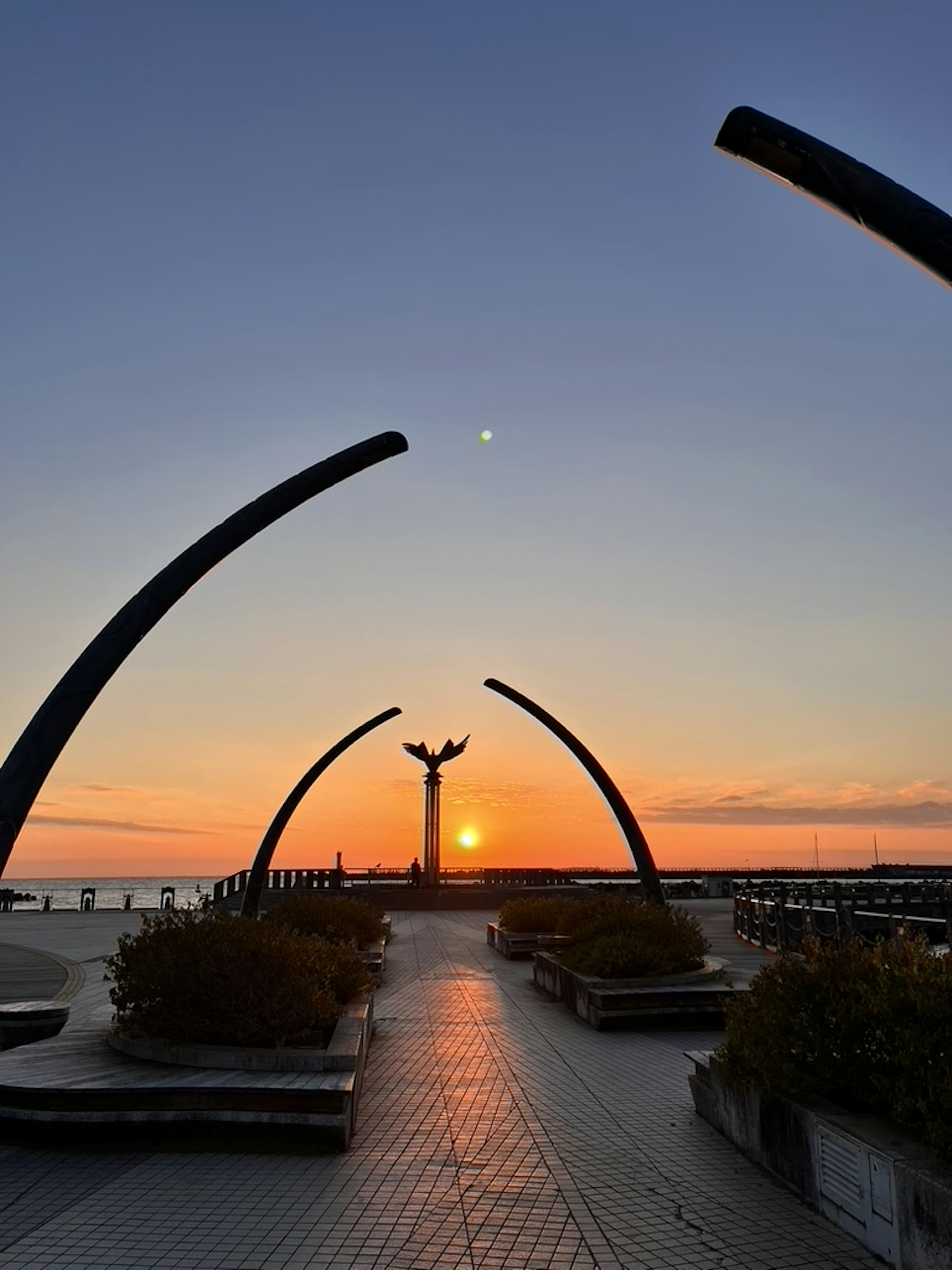 Skulptur und Bogenstrukturen in einem Park am Meer bei Sonnenuntergang