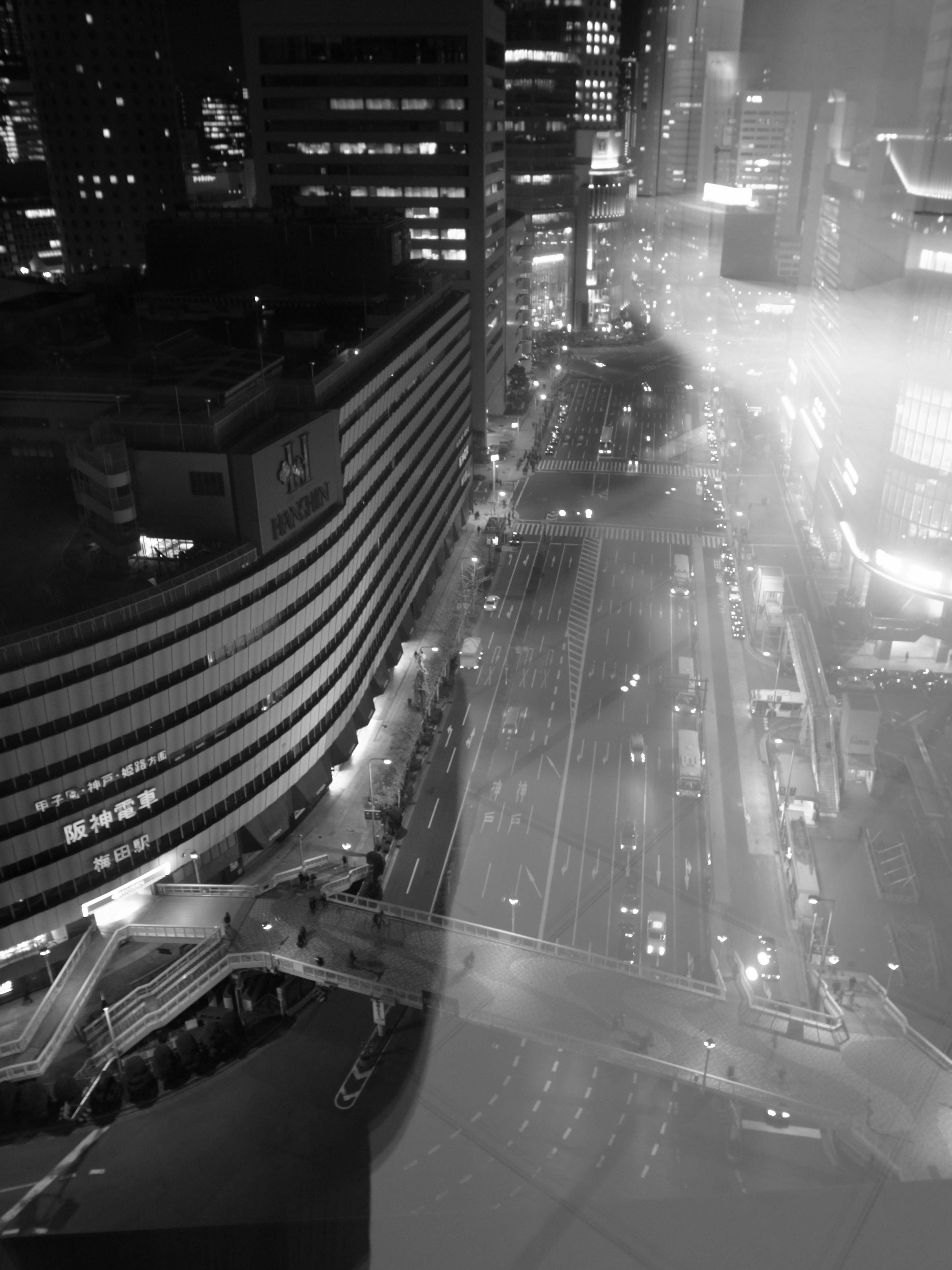 Black and white cityscape at night featuring skyscrapers and a busy intersection