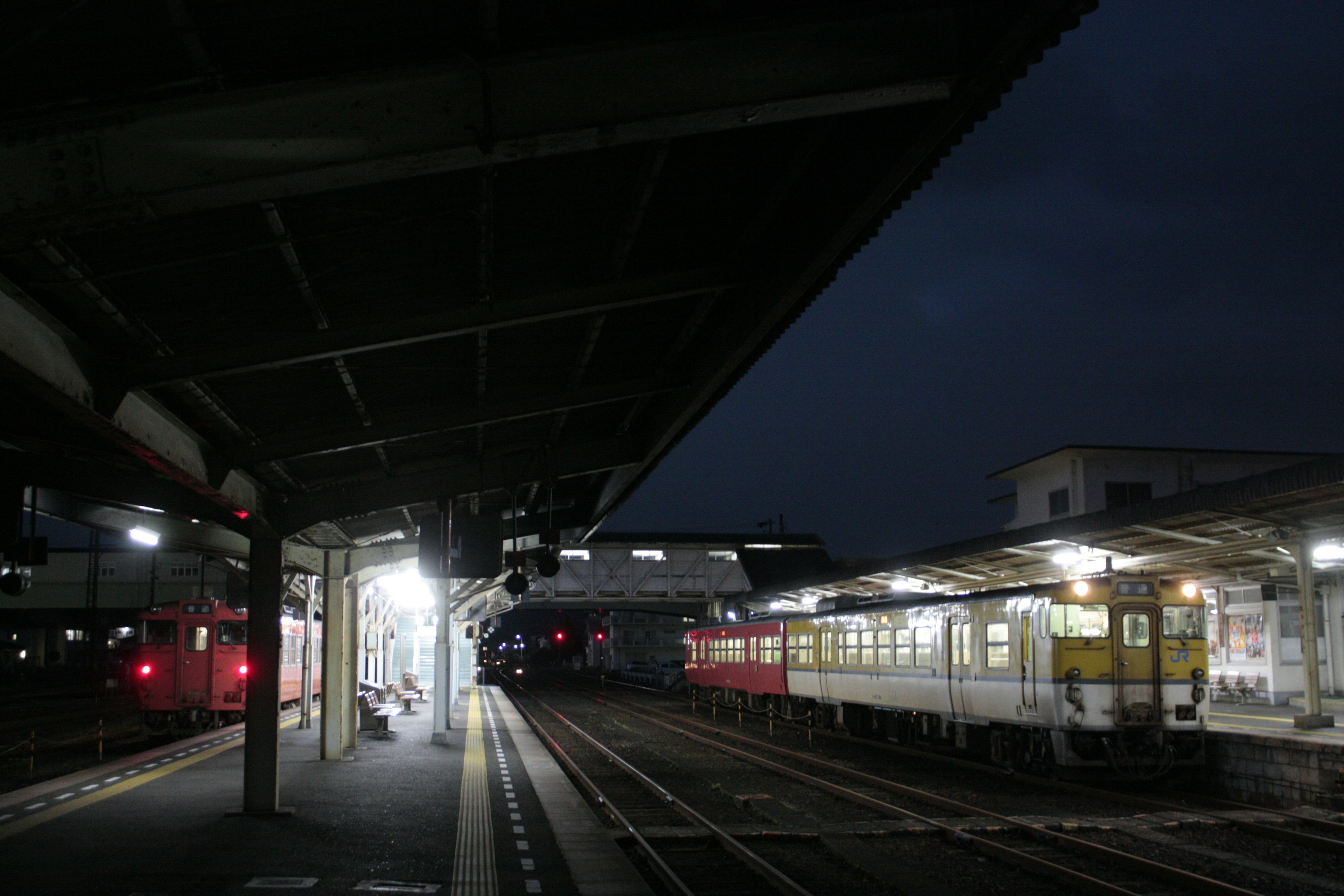 Train station at night with illuminated platform and parked trains