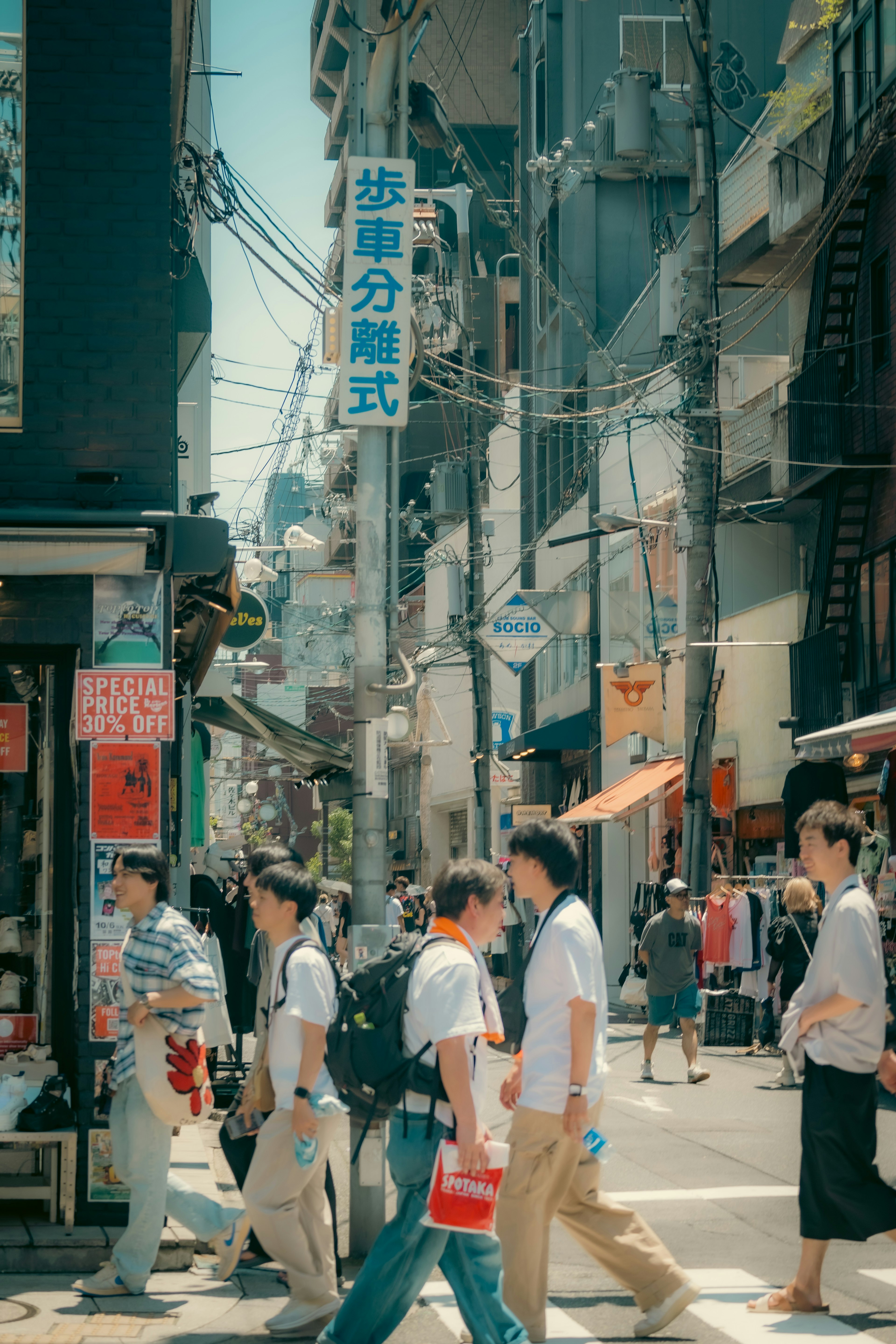 Scena di strada affollata a Tokyo con persone che camminano e negozi lungo la strada