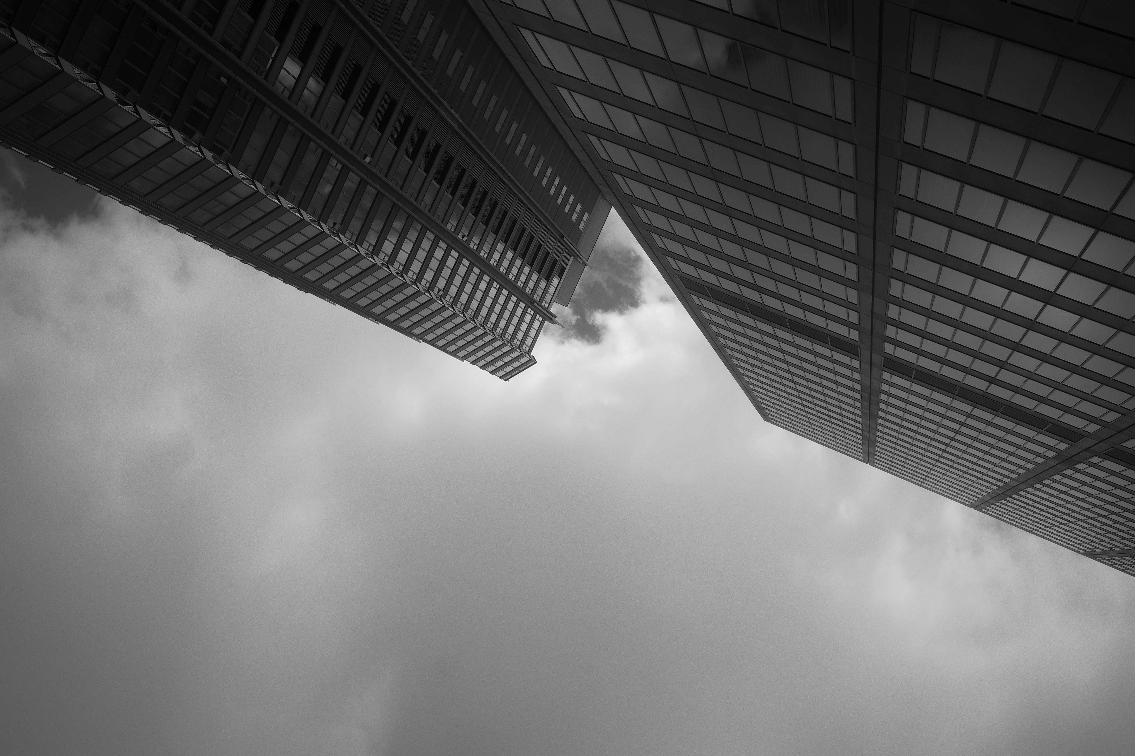 Monochrome image of skyscrapers viewed at an angle with clouds in the sky