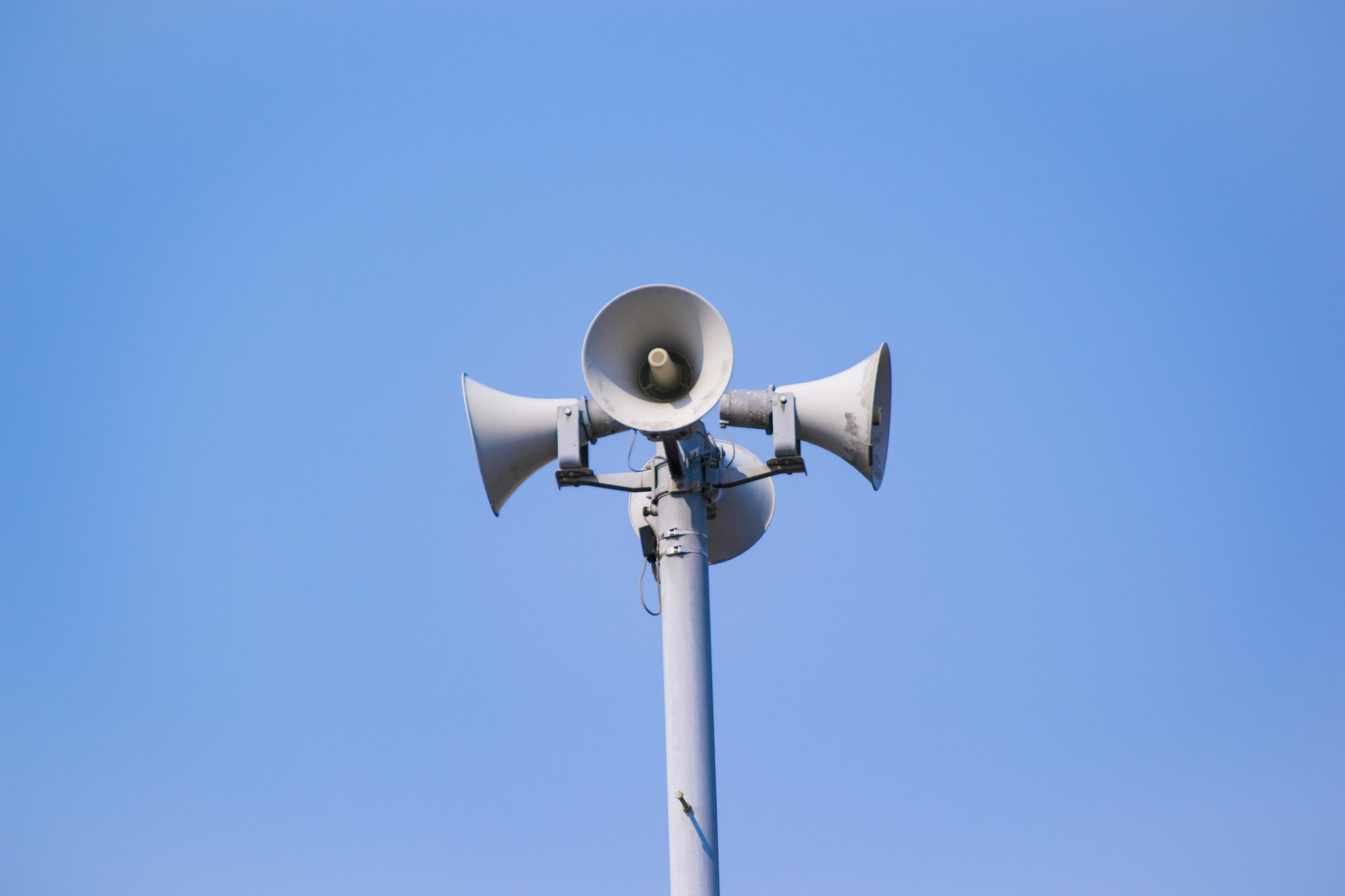 Conjunto de altavoces en un poste bajo un cielo azul